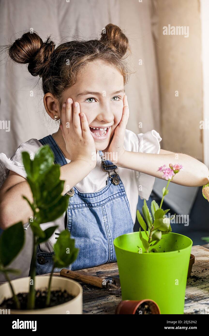 cute cheerful caucasian girl is laughing while gardening. spring flower planting with children. happy moments. front view. close-up. Stock Photo