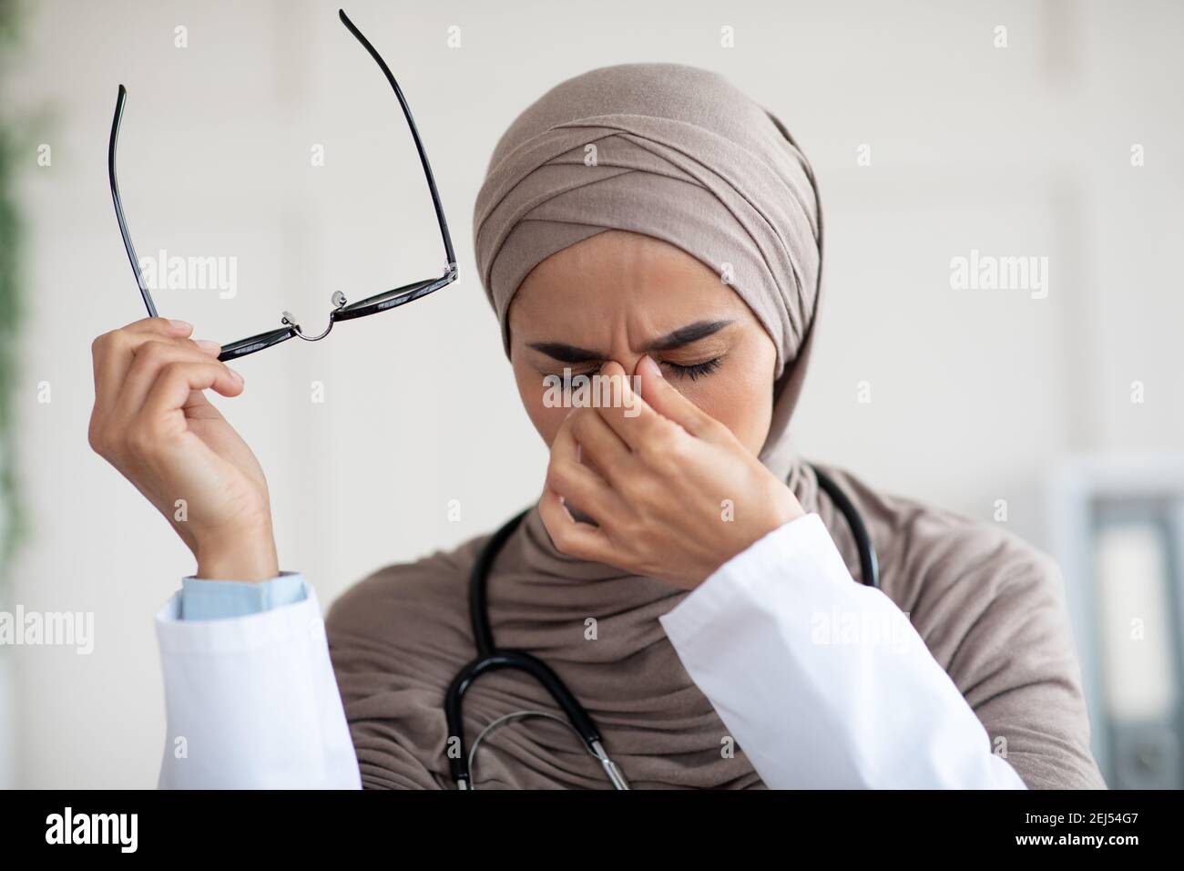 Closeup of female doctor removing glasses and rubbing nose bridge Stock