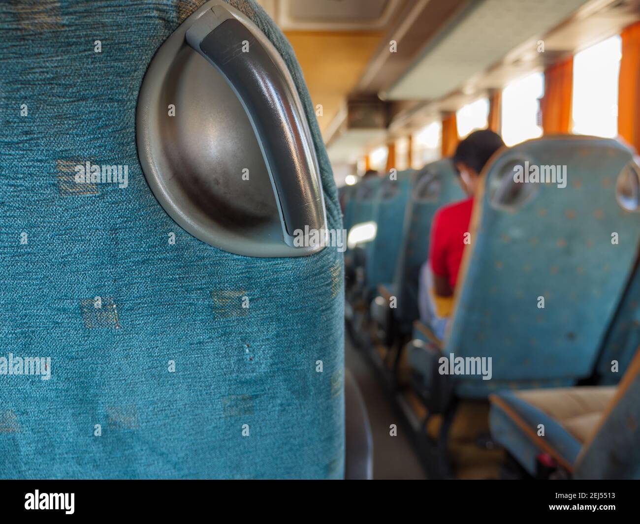 Closeup of a handgrip of a passenger seat in a bus riding from one town to another. The person sitting in the background. Stock Photo