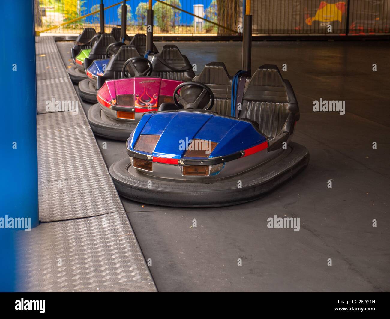 Electric colorful old-fashioned bumper cars for two standing in a row in a city amusement park. Traditional family entertainment and active rest. Stock Photo