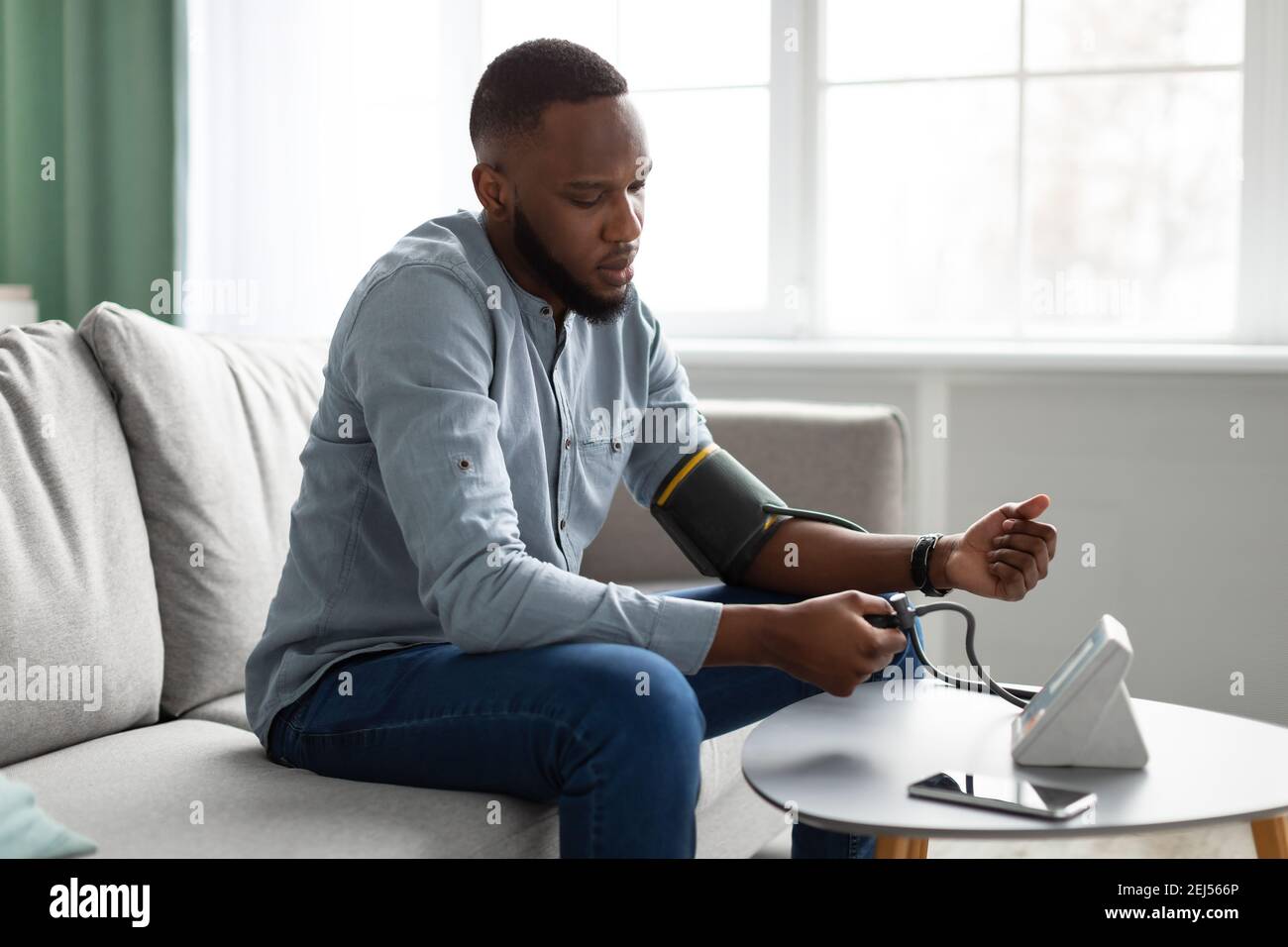 Black Young Man Measuring Arterial Pressure Feeling Bad At Home Stock Photo