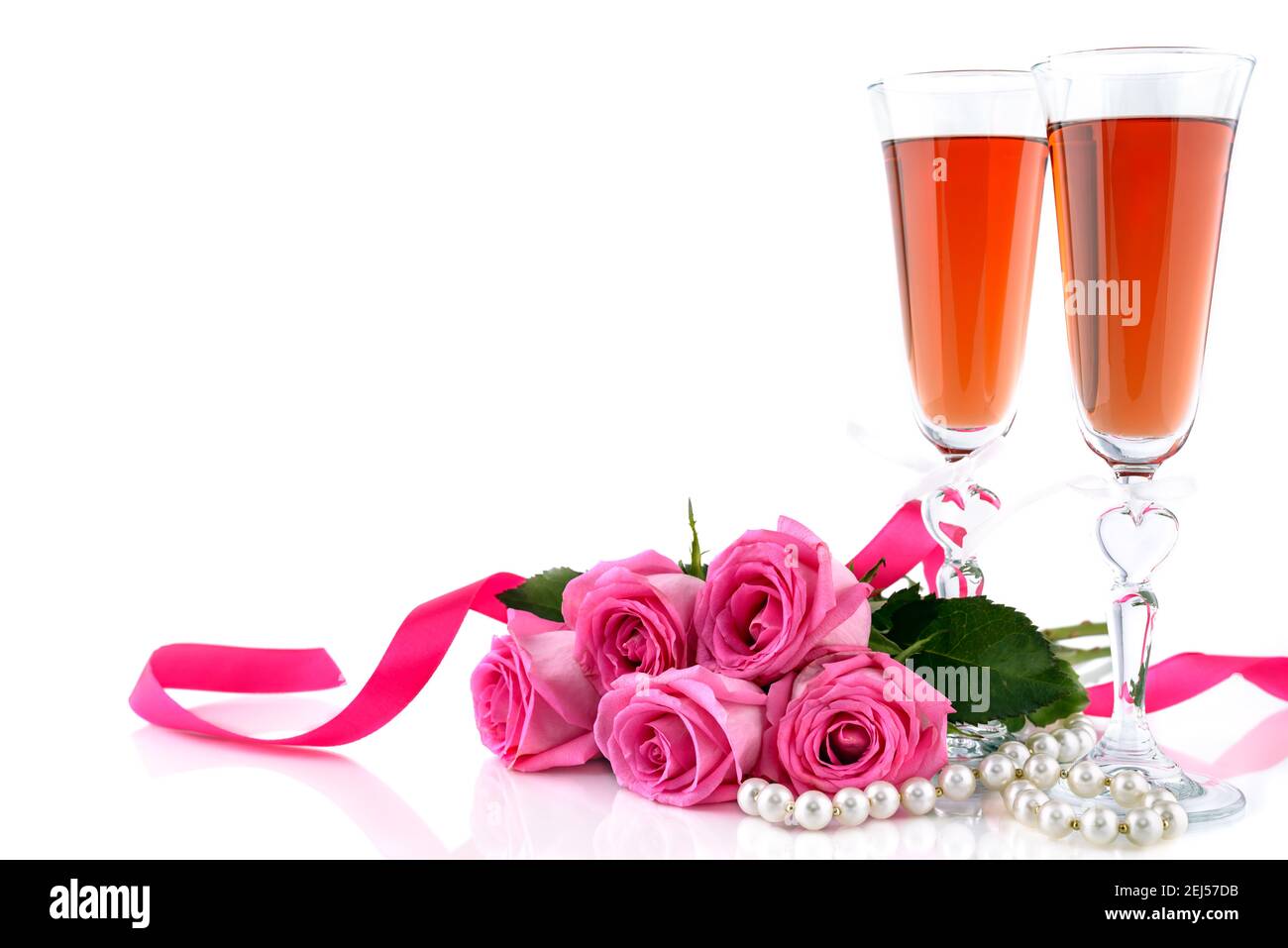 Valentine's Day concept. Two glasses of wine, red roses and string of pearls on a white background with copy space for text. Selective focus. Stock Photo