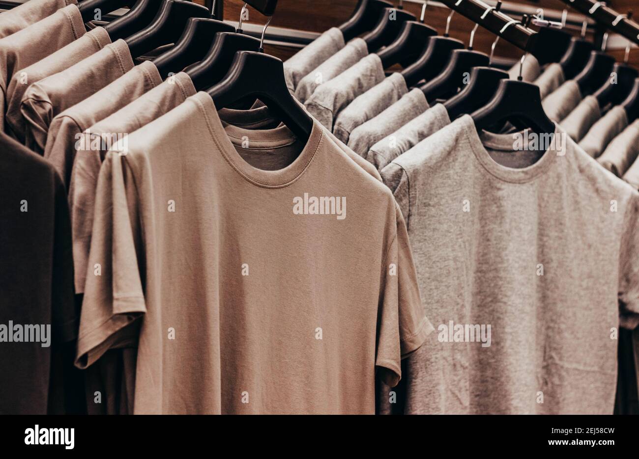 Close-up photo of olive colored soldier tactical t-shirts hanging on stand rack. Stock Photo
