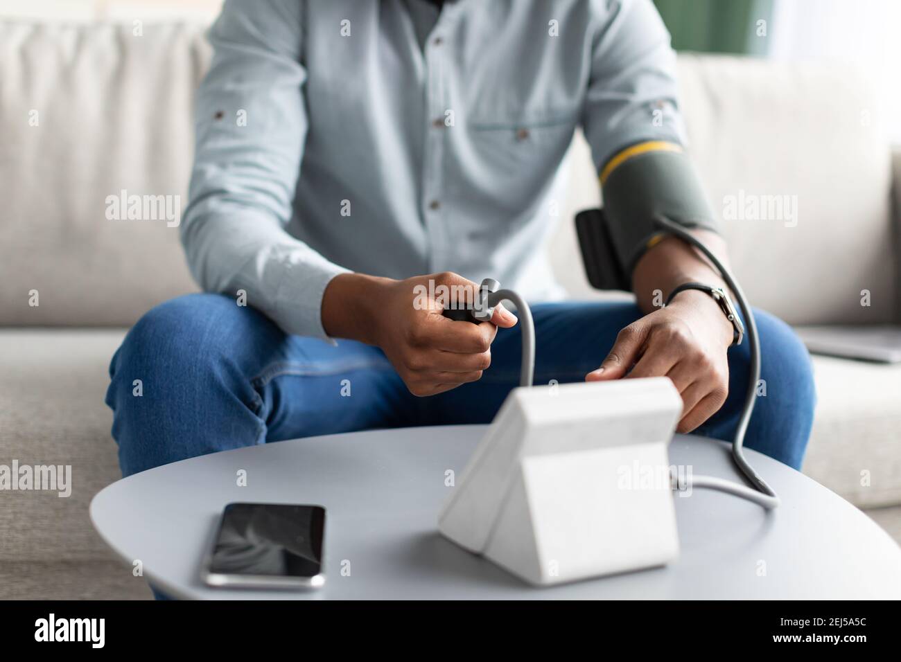 Unrecognizable African Man Measuring Arterial Pressure Having Hypertension At Home Stock Photo