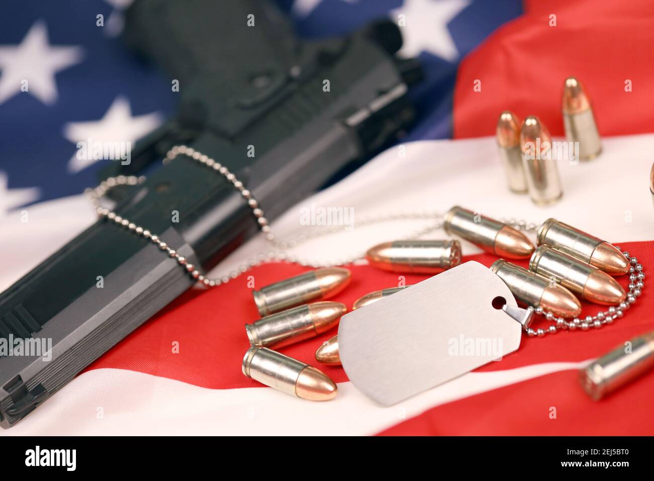 Many yellow 9mm bullets and gun with dogtags on United States flag. Concept of duty and service in US army forces. Veteran concept Stock Photo