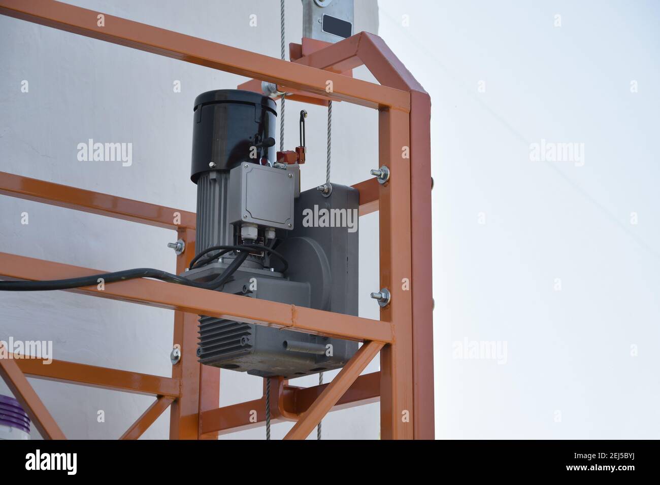 Hoist supply and safety lock as part of suspended wire rope platform for facade works on high multistorey buildings. Hoist for elevation, raising or l Stock Photo