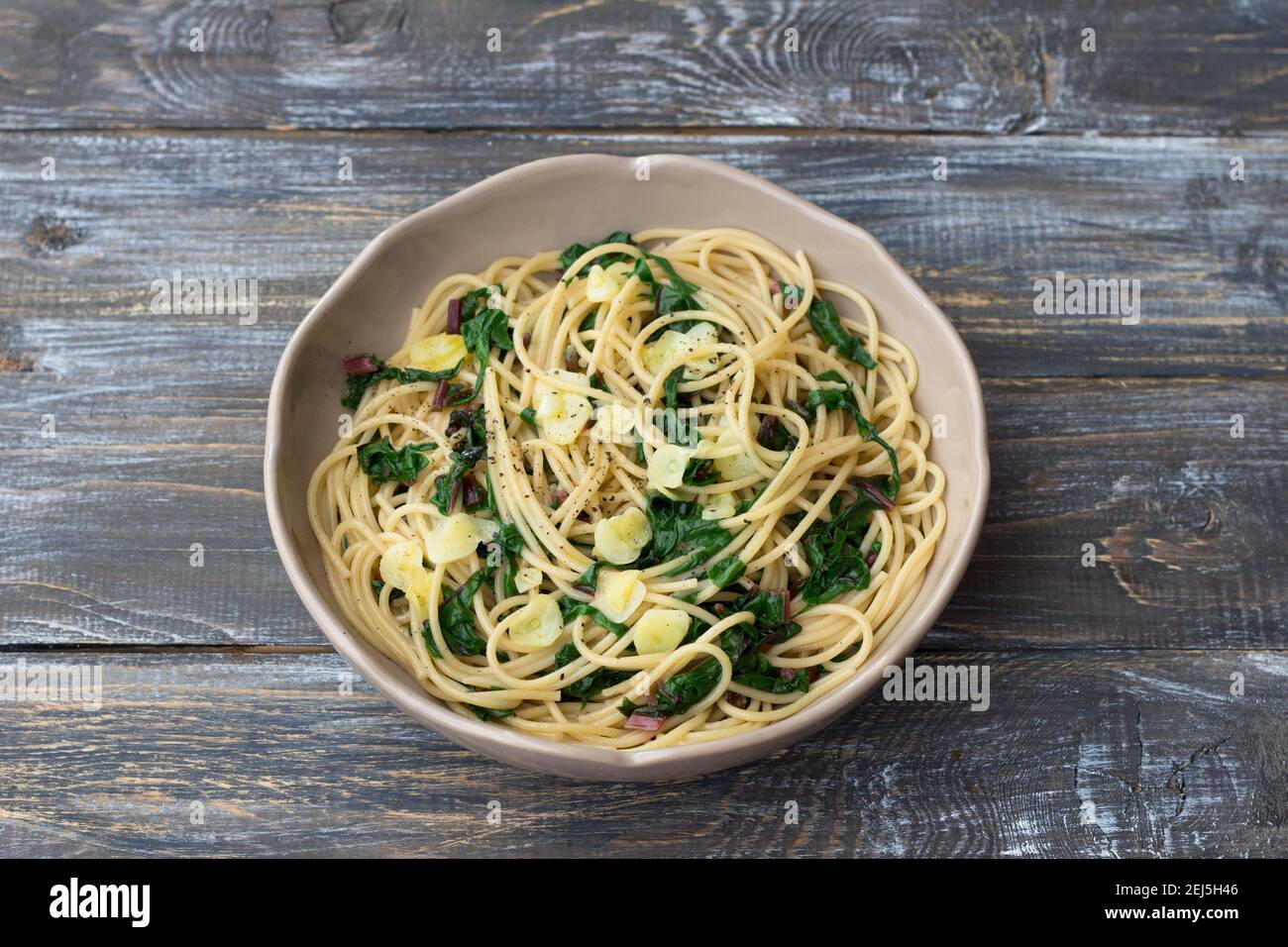 Vegan spaghetti with chard and garlic on a wooden table. Delicious homemade food Stock Photo