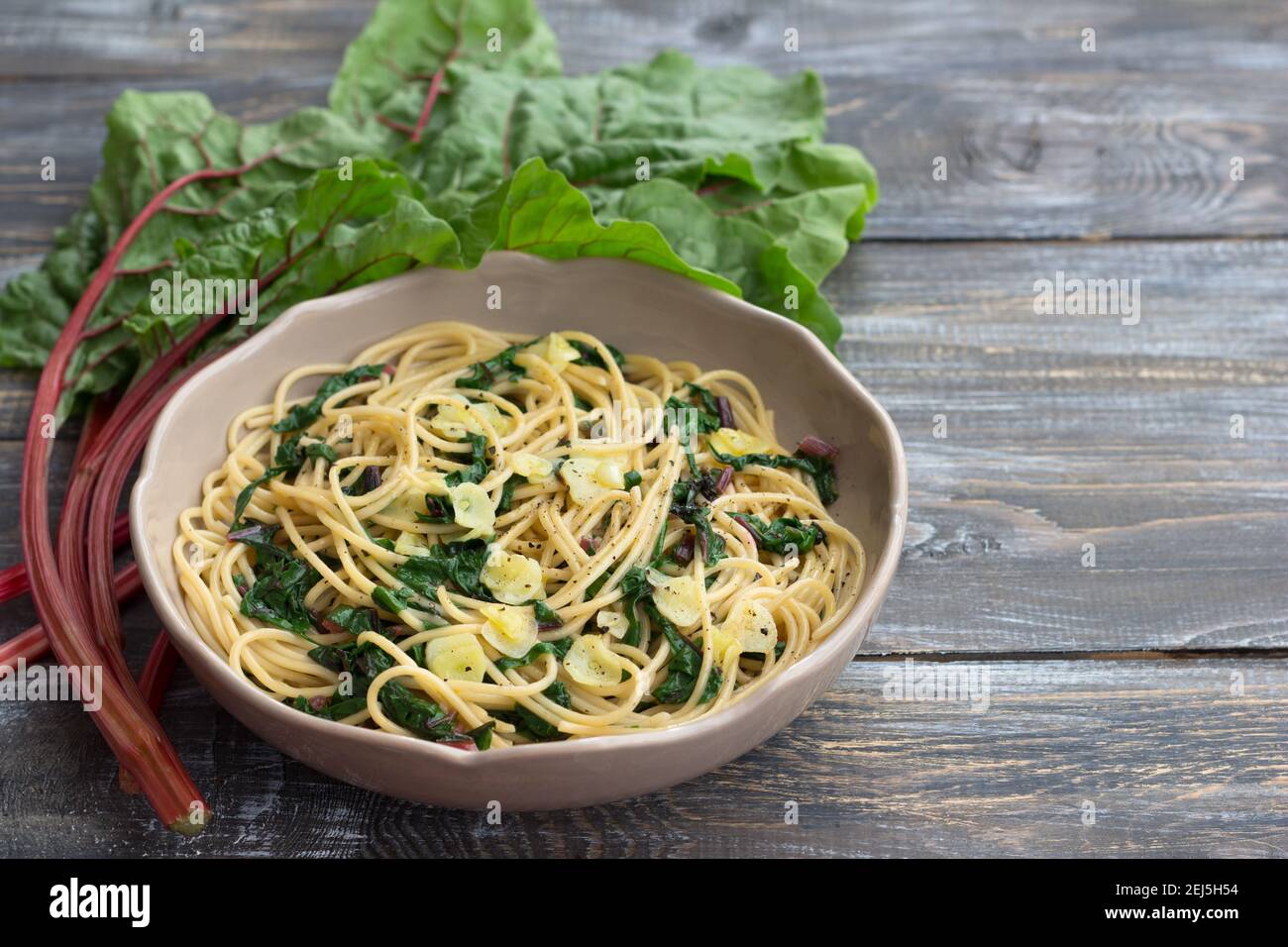 Vegan spaghetti with chard and garlic on a wooden table. Delicious homemade food Stock Photo