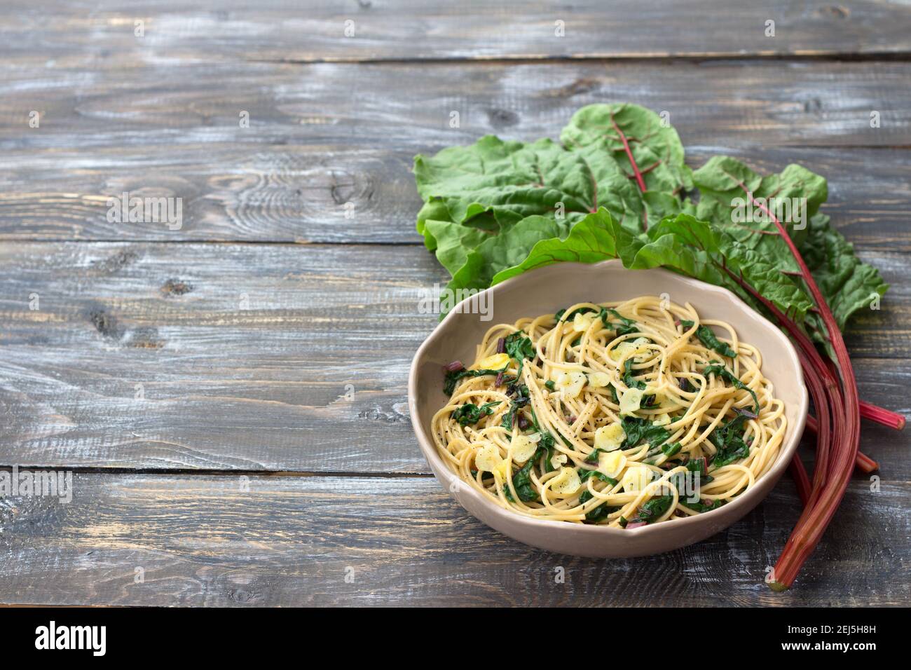 Vegan spaghetti with chard and garlic on a wooden table. Delicious homemade food Stock Photo