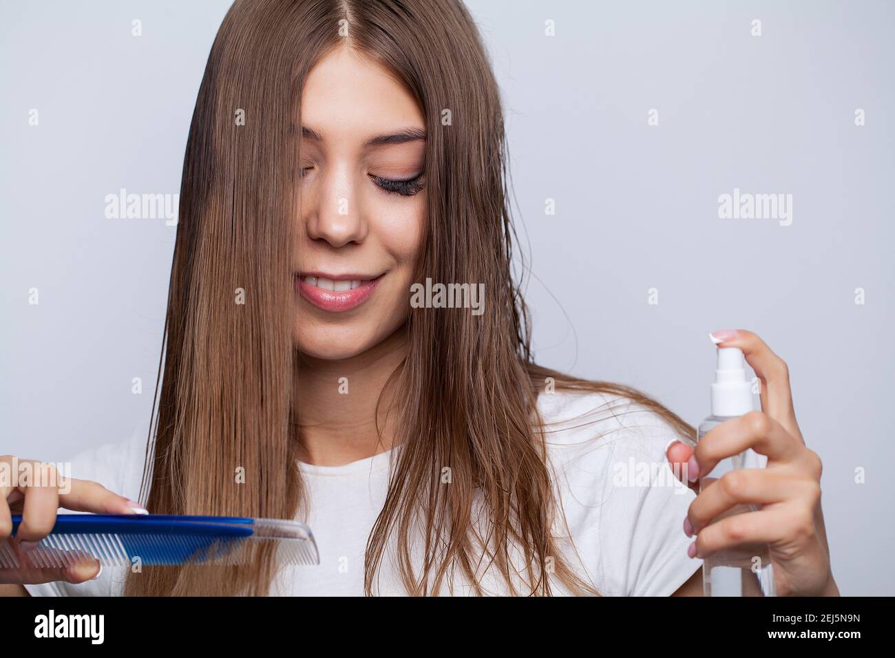 Young woman applying oil onto hair in bathroom Stock Photo Alamy
