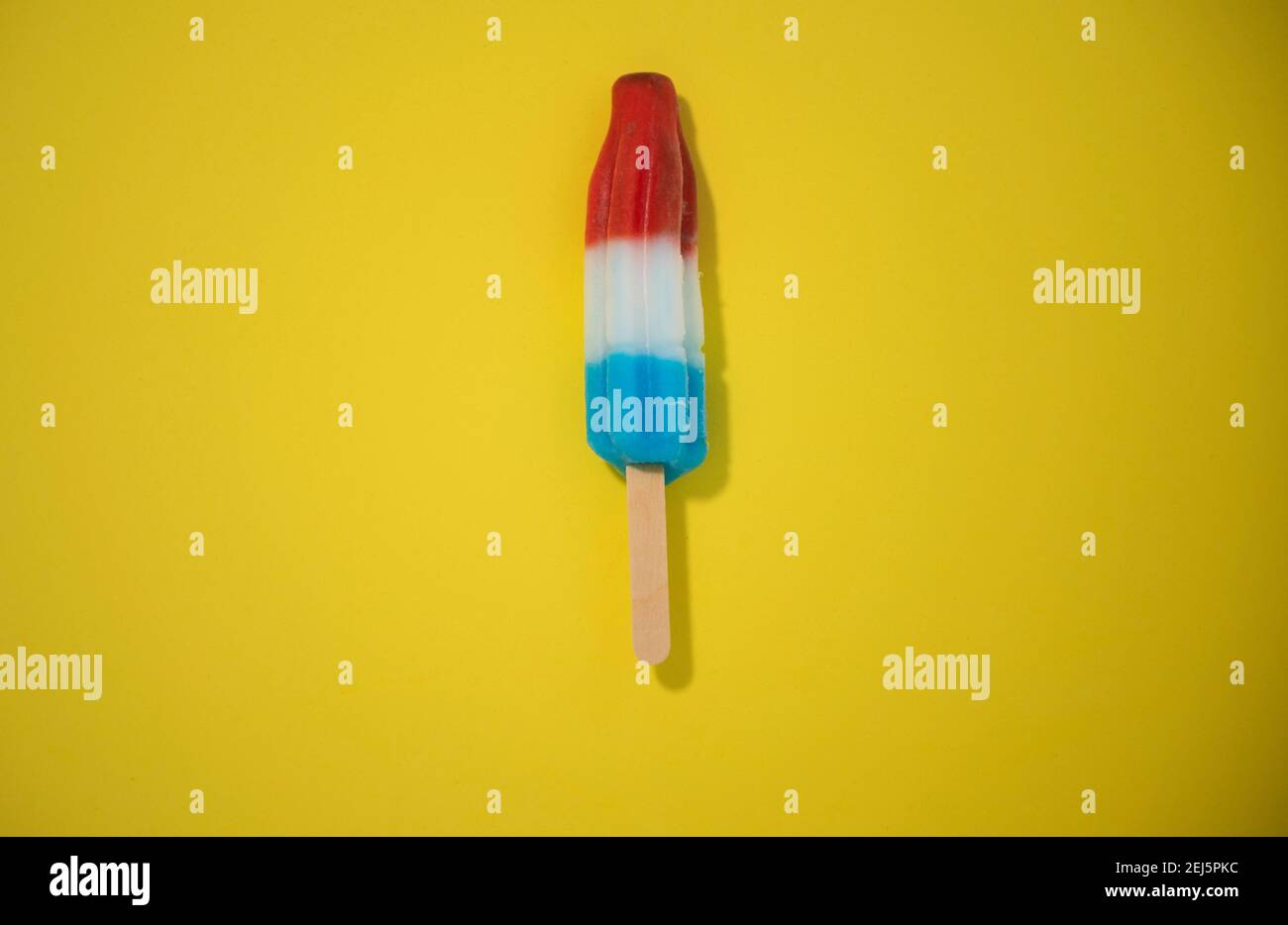 Red, White and Blue Novelty ice cream bombpop shot on yellow background, stop action animation exploding like fireworks. Series 1 of 8. Stock Photo