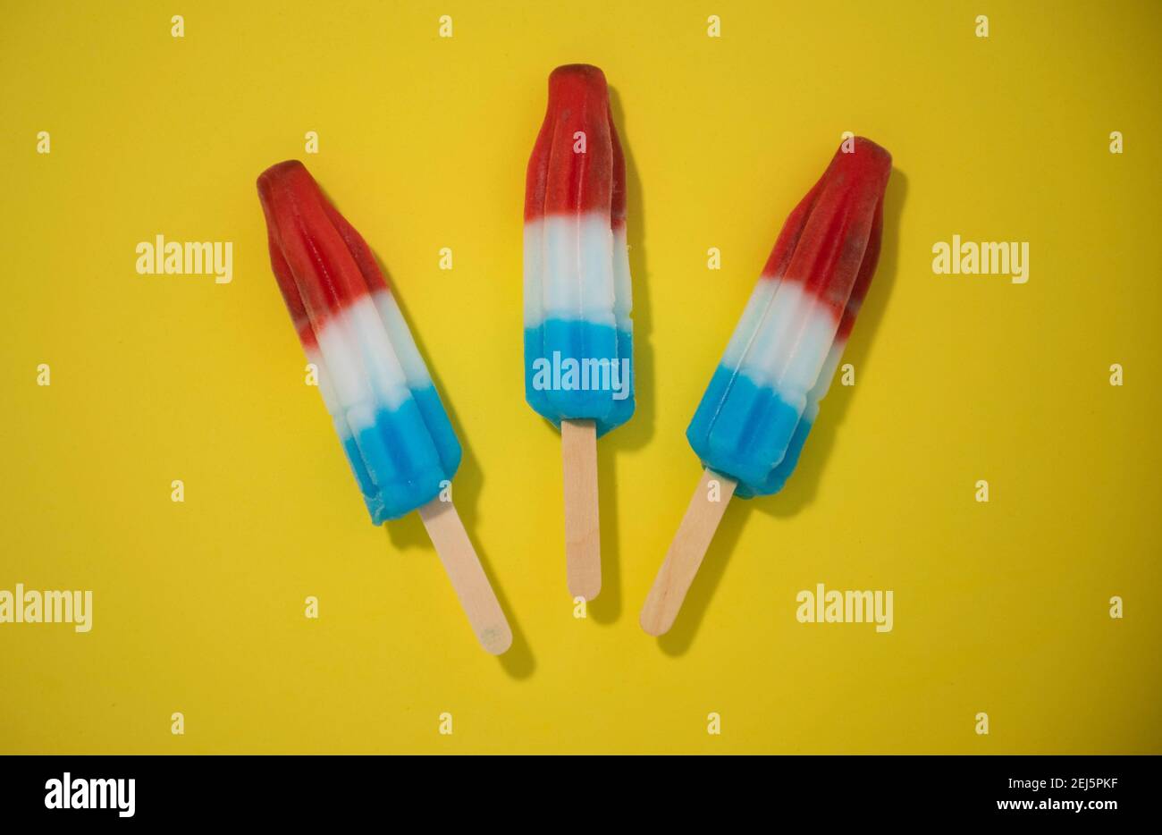 Red, White and Blue Novelty ice cream bombpop shot on yellow background, stop action animation exploding like fireworks. Series 2 of 8. Stock Photo
