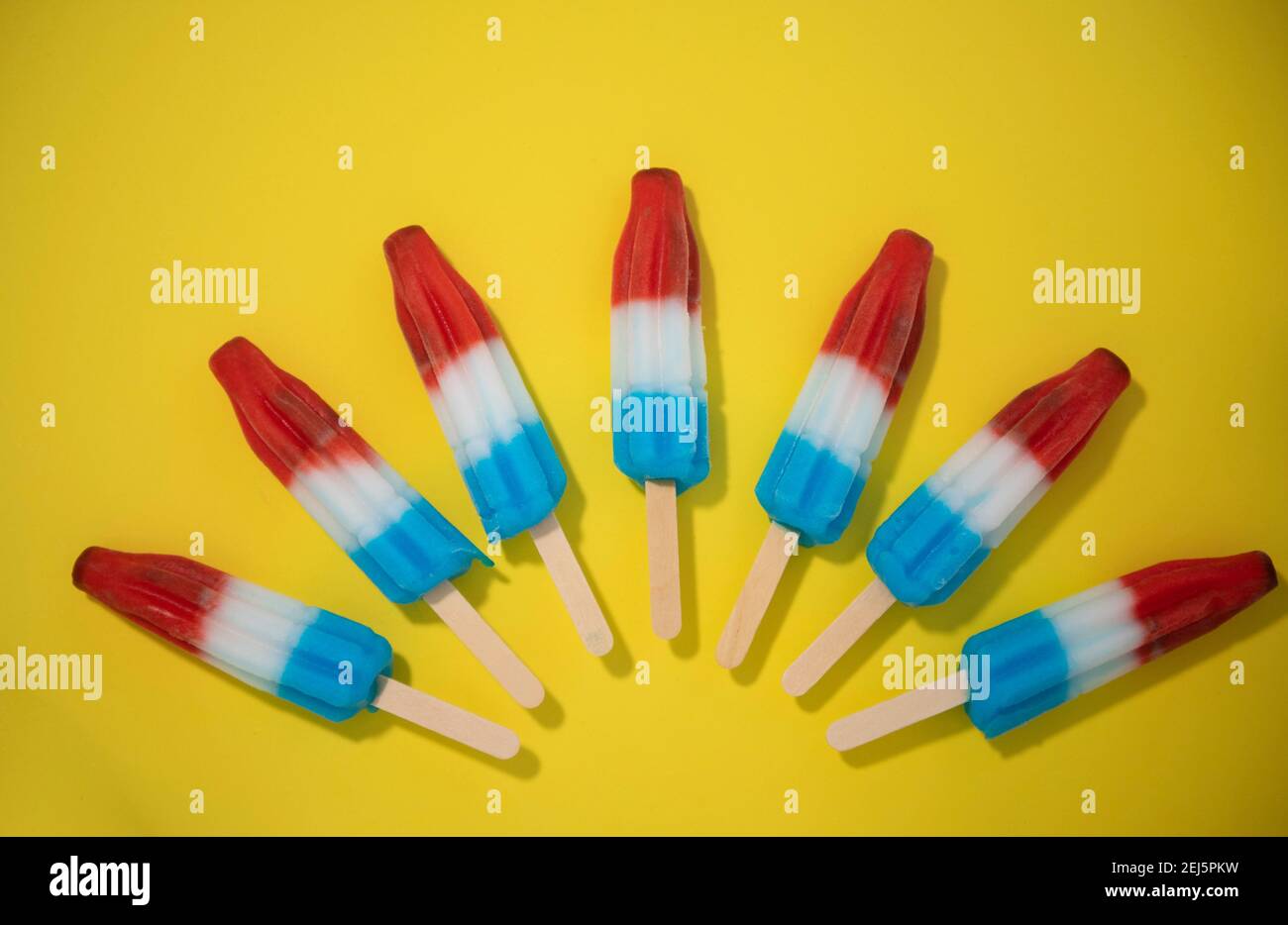 Red, White and Blue Novelty ice cream bombpop shot on yellow background, stop action animation exploding like fireworks. Series 4 of 8. Stock Photo
