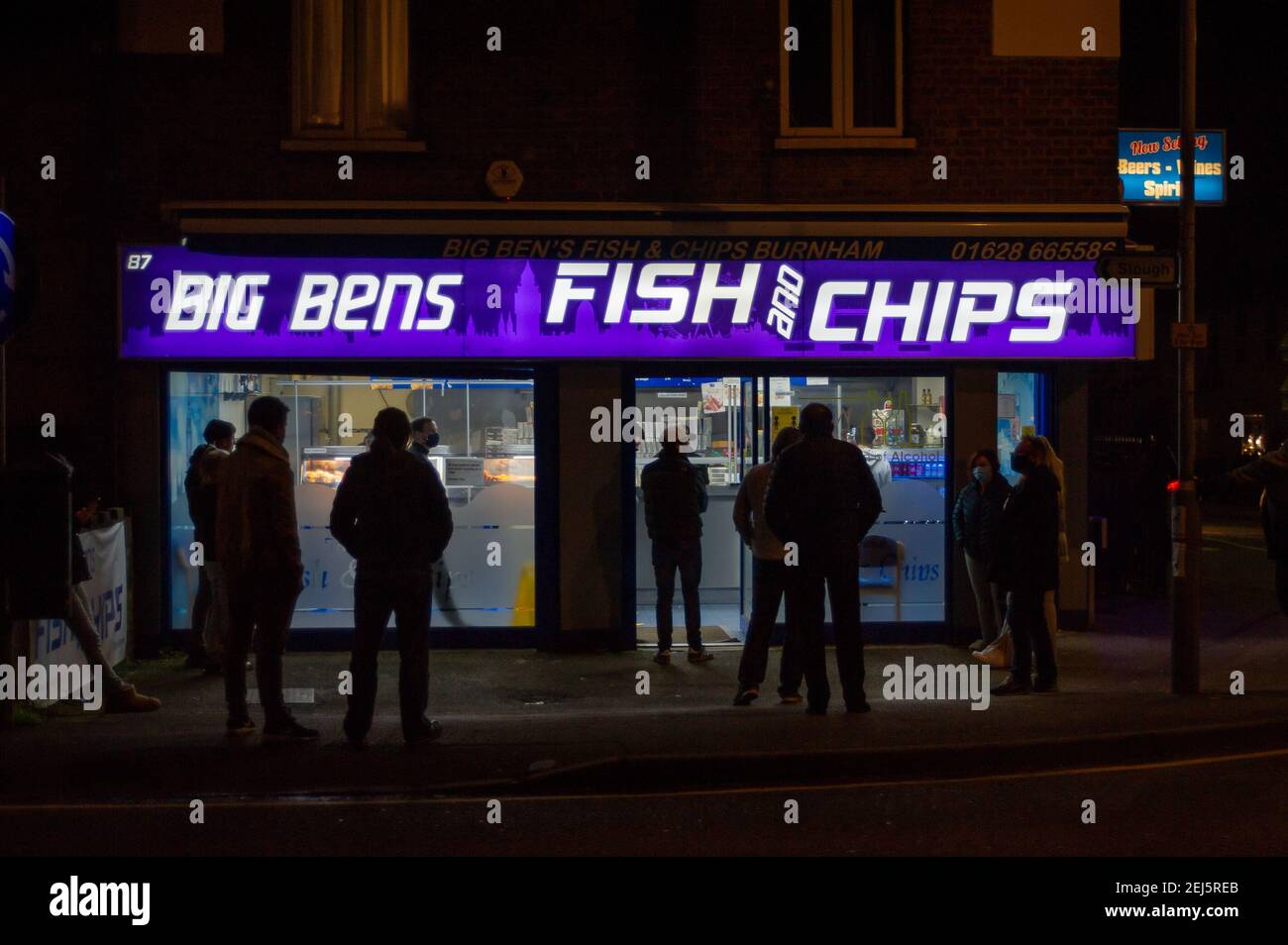 Burnham, Slough, Berkshire, UK. 20th February, 2021. People make a socially distanced queue outside Big Ben's Fish and Chips shop in Slough. Take aways have been very popular during the Covid-19 Coronavirus lockdown. Credit: Maureen McLean/Alamy Stock Photo