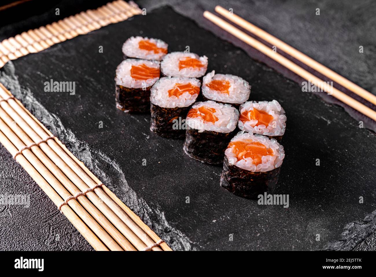 Classic Japanese sushi roll with salmon. Black background and black decor. Stock Photo