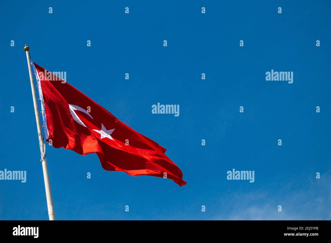 Turkish national flag with white star and moon on a pole in sky Stock