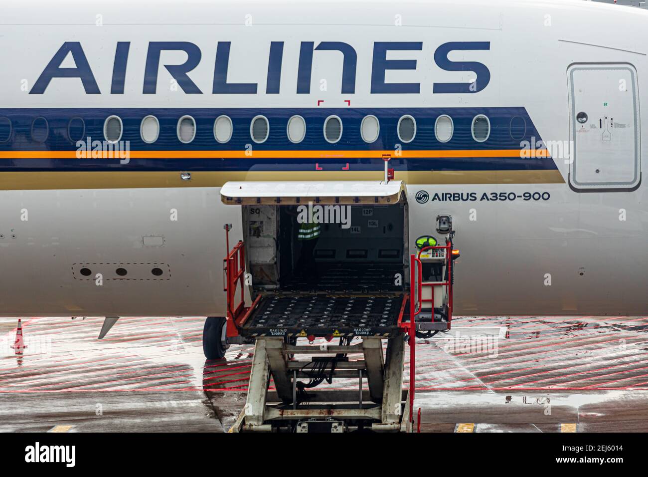 A ULD loader for lifting unit load devices (ULD) to an aircraft's cargo bay of a Singapore Airlines machine and a ULD transporter at Changi Airport Stock Photo