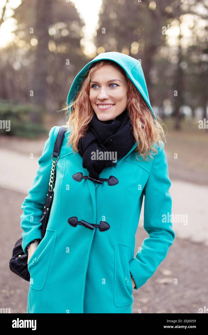 Happy young redhead Caucasian woman walking at park in cold weather Stock Photo