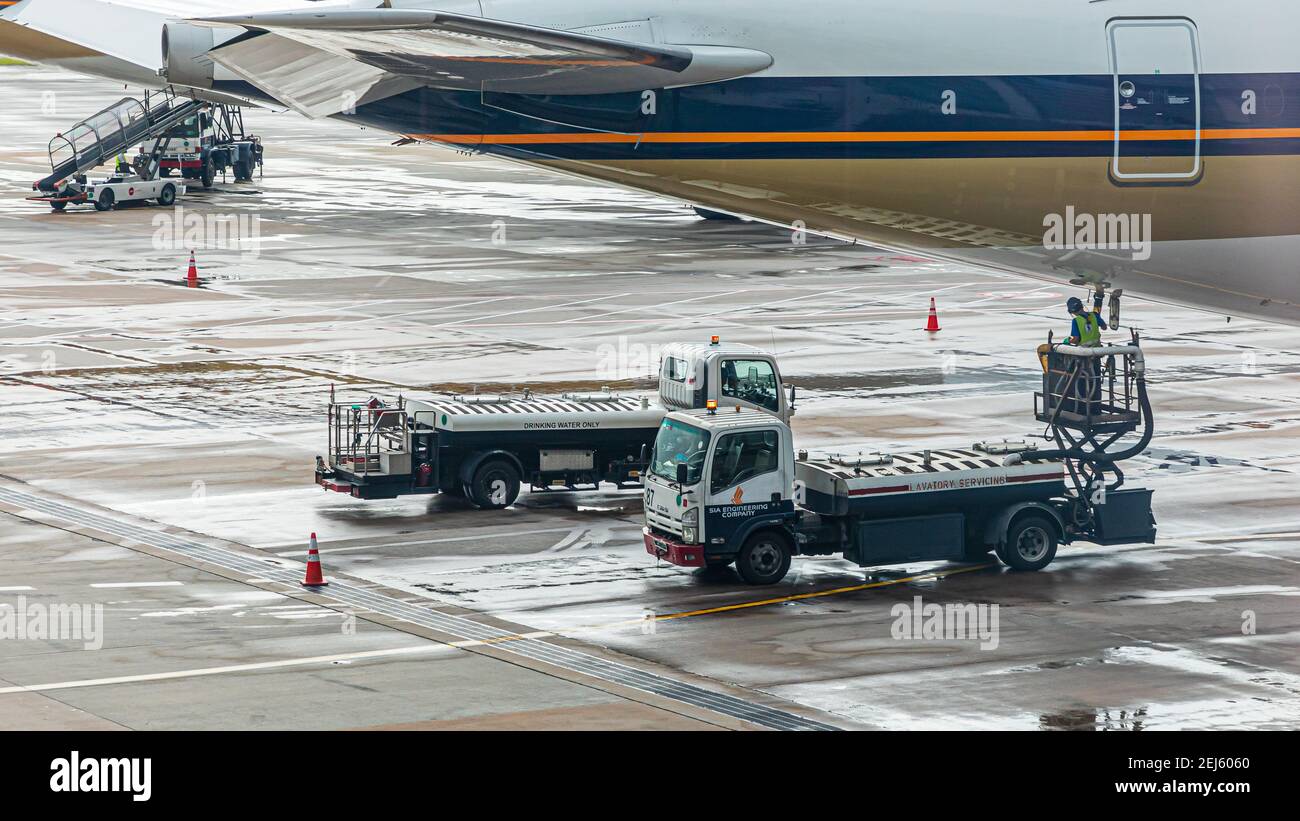 Lavatory service vehicles for emptying and refilling lavatories onboard aircraft of a Singapore Airlines machine at apron of Changi Intern. Airport Stock Photo