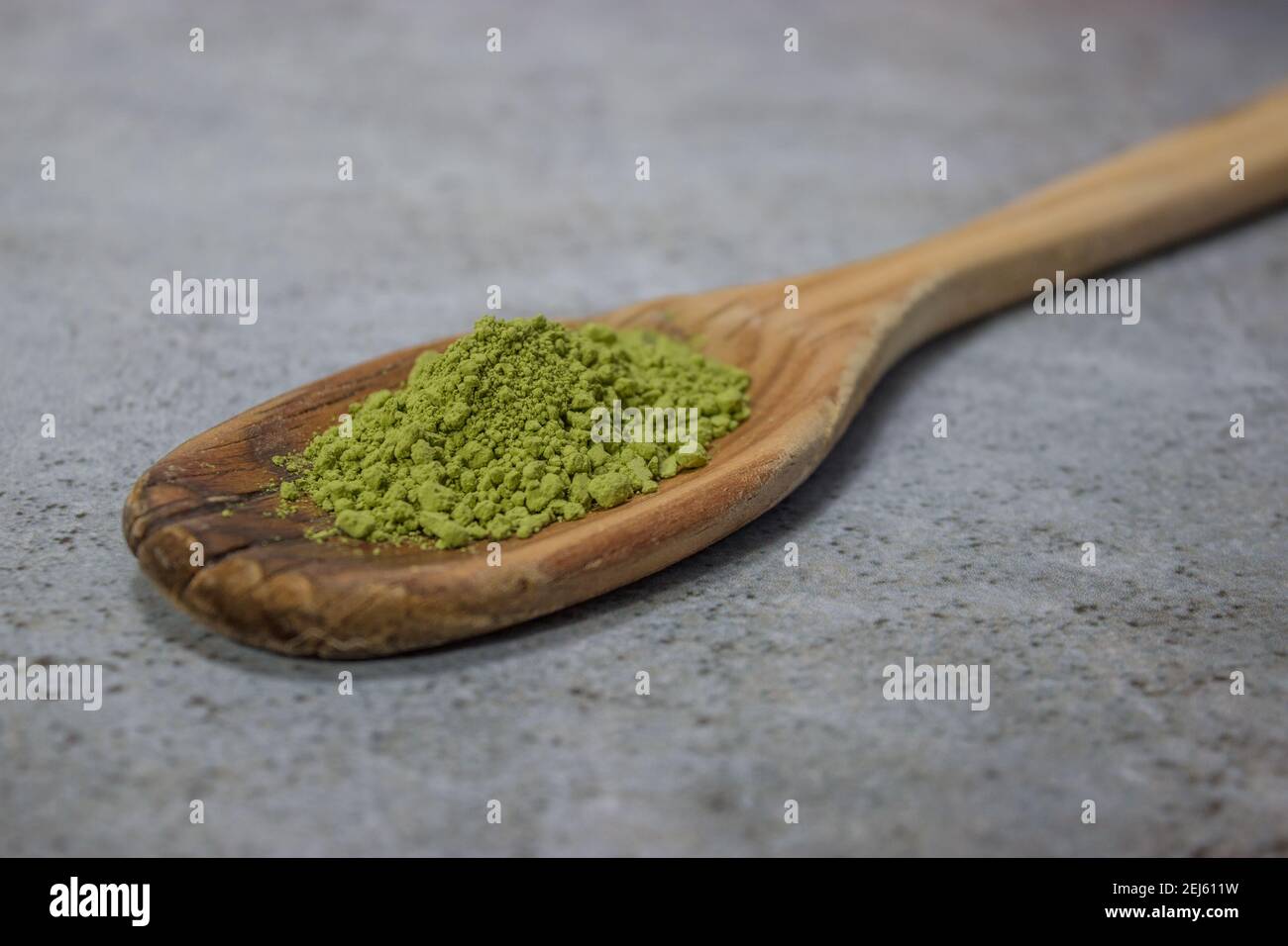 Close up matcha tea powder on wooden spoon on Gray Stone Background. Japanese Green Tea Concept