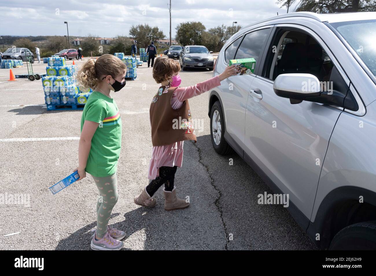 Oak Hill, TX USA Feb. 21, 2021: Children pass out free Girl Scout cookies as other volunteers pass out cases of bottled water to desperate western Travis County, TX residents out of tap water for several days due to last week's devastating Texas snowstorm. Drivers were only allowed one case per car after some waited in line for three hours. Credit: Bob Daemmrich/Alamy Live News Stock Photo