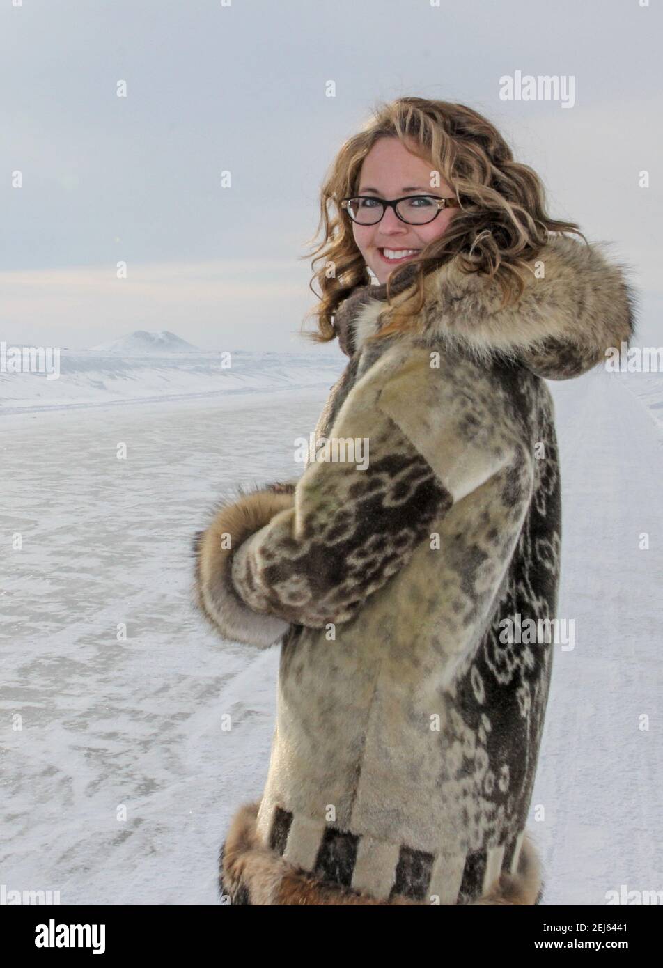 Caucasian woman in her 30s, dressed in traditional Inuit sealskin fur parka, standing on the Arctic Ocean ice road, Northwest Territories, Canada. Stock Photo