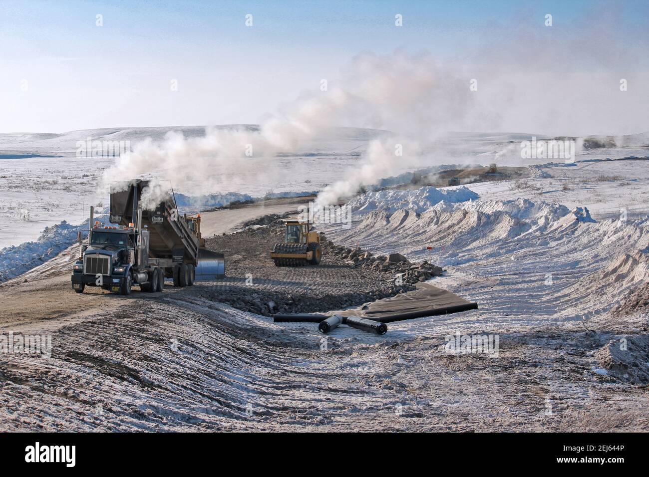 Trucks laying gravel along the Inuvik-Tuktoyaktuk Highway on top of geotextile fabric (protects permafrost), Northwest Territories, Canada’s Arctic. Stock Photo