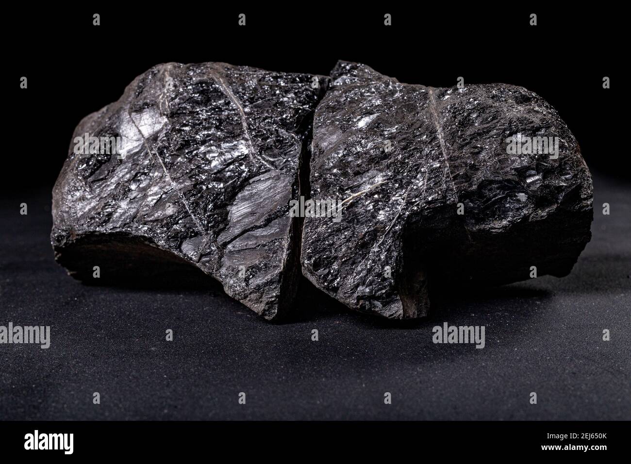 A lump of brown coal laid on a table. Mineral used to generate energy. Dark background. Stock Photo