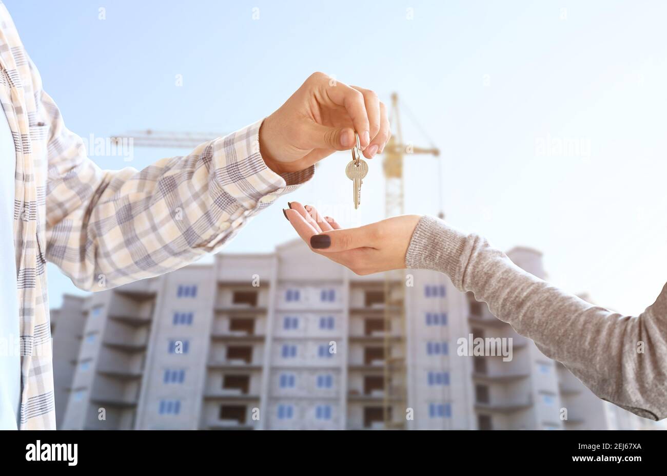 Real estate agent giving a key from new house to woman near unfinished ...