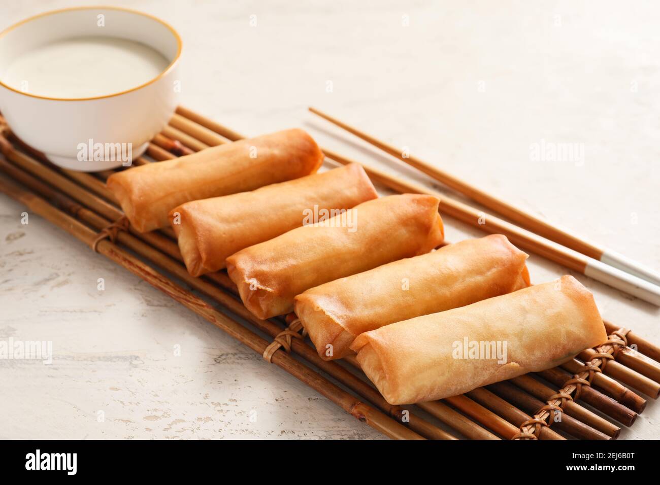 Tasty fried spring rolls and sauce on light background Stock Photo