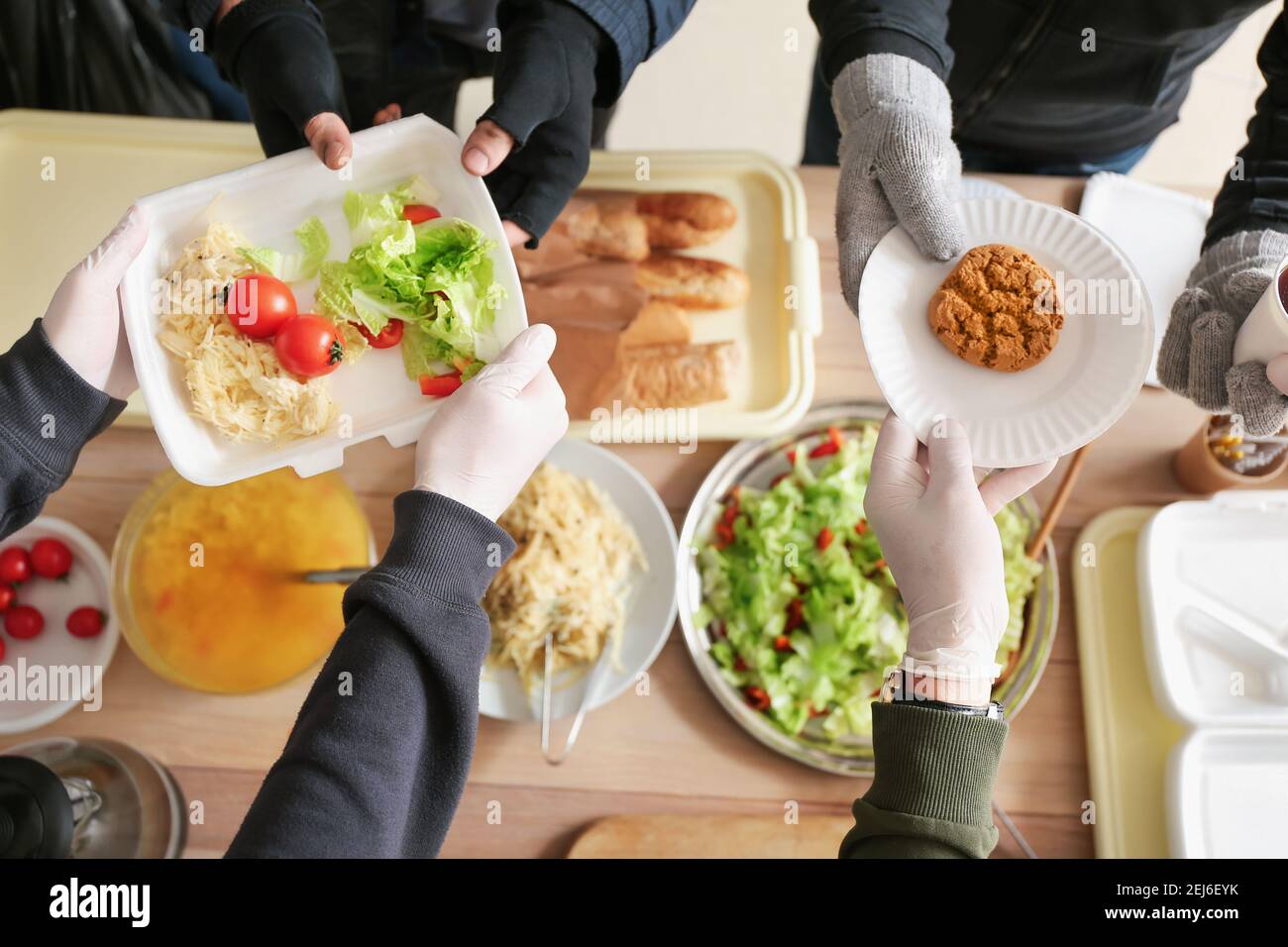 Volunteers giving food to homeless people in warming center Stock Photo