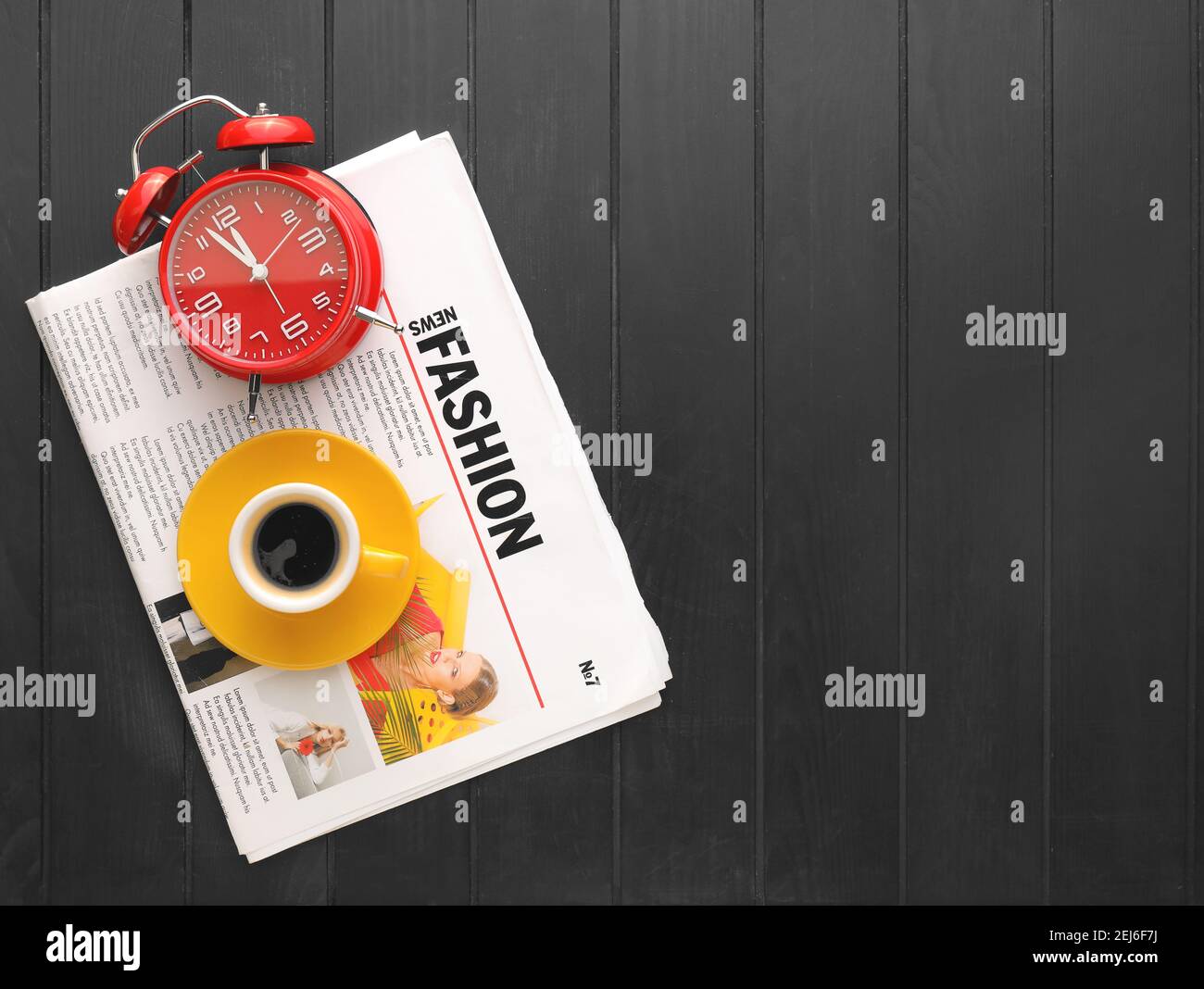 Alarm clock, newspaper and cup of coffee on black background Stock