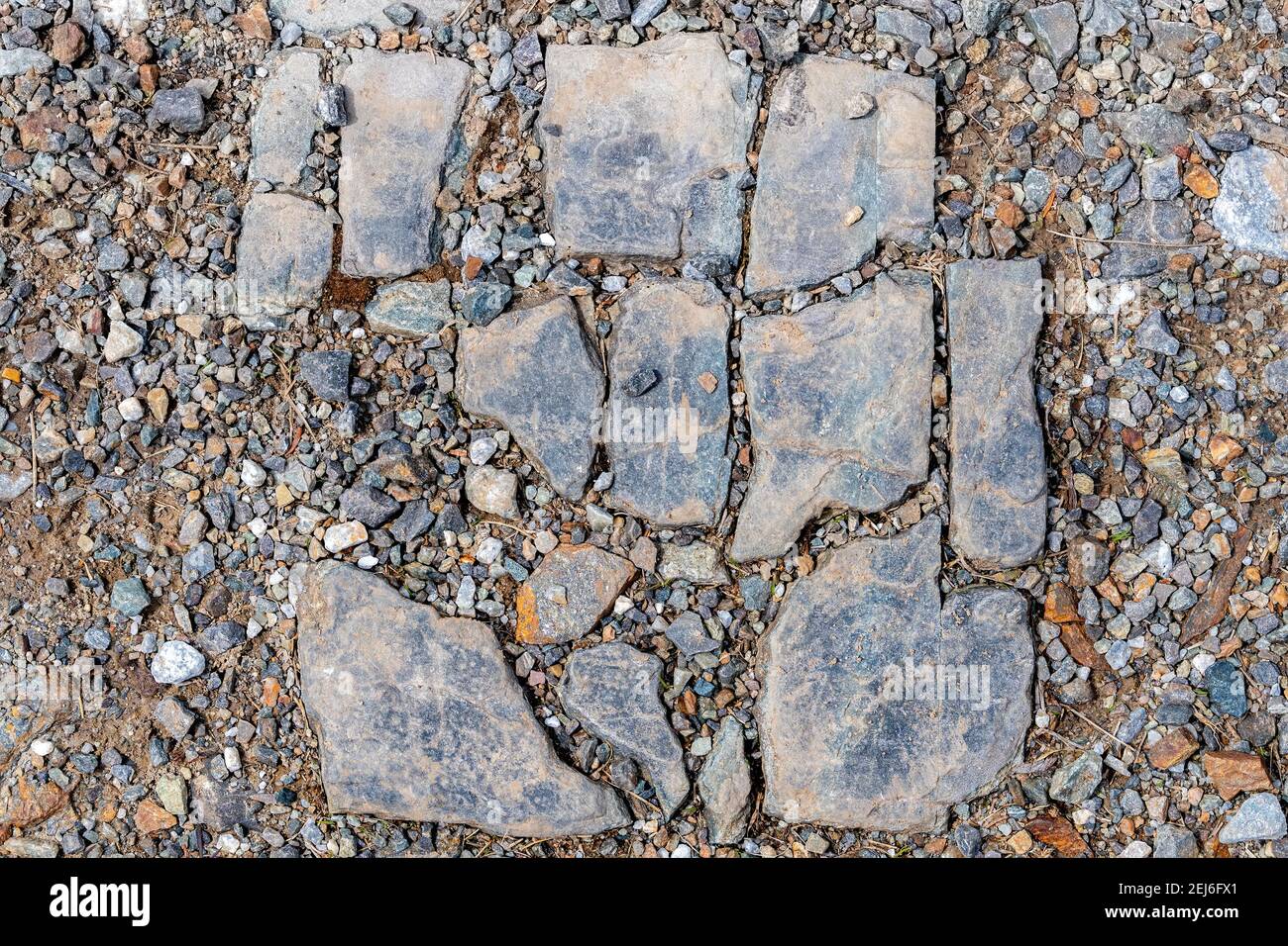 A dirty broken stone tile on gravel. The tile is arranged to it is obvious how it fit together before it was broken. Some bits missing. Stock Photo