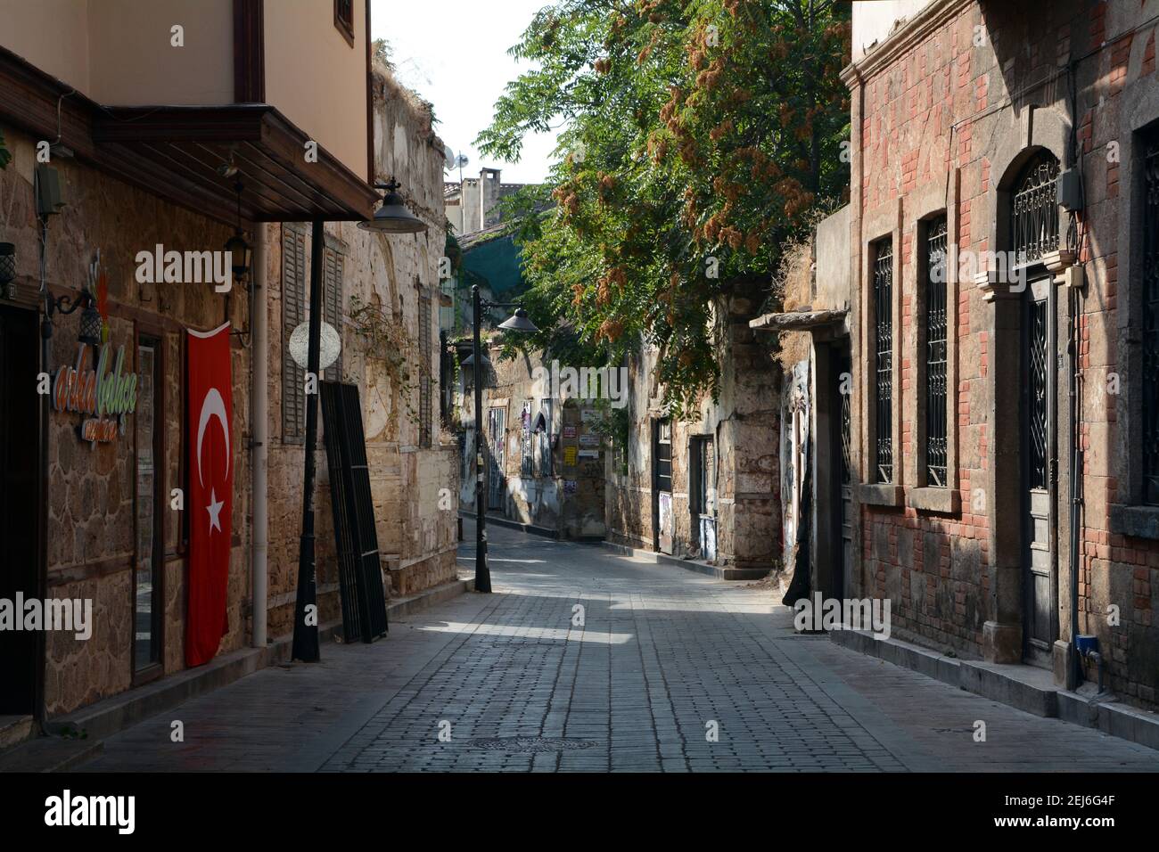 Quiet and empty side street in Antalya old town early in the morning. The Turkish flag hanging from one wall. Sep 2015 Stock Photo