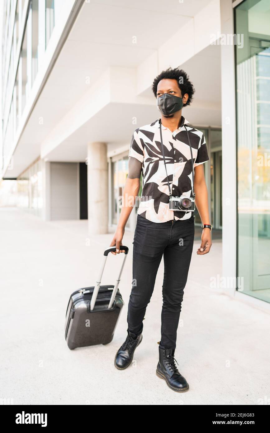 Tourist man carrying suitcase while walking outdoors Stock Photo - Alamy