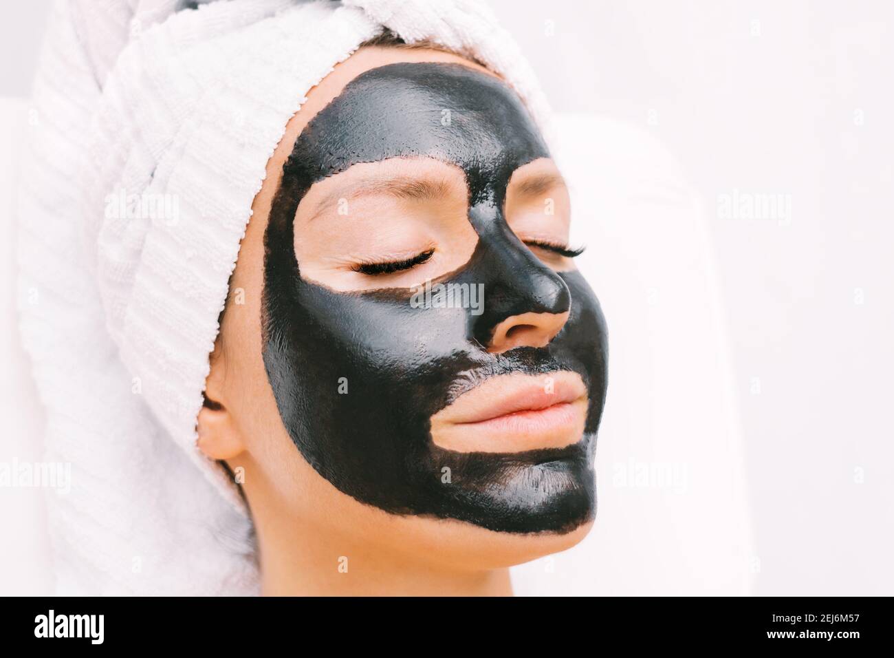 Woman with black purifying charcoal facial mask in spa. Cosmetology and skincare. Beauty treatments. Spa therapy. Stock Photo