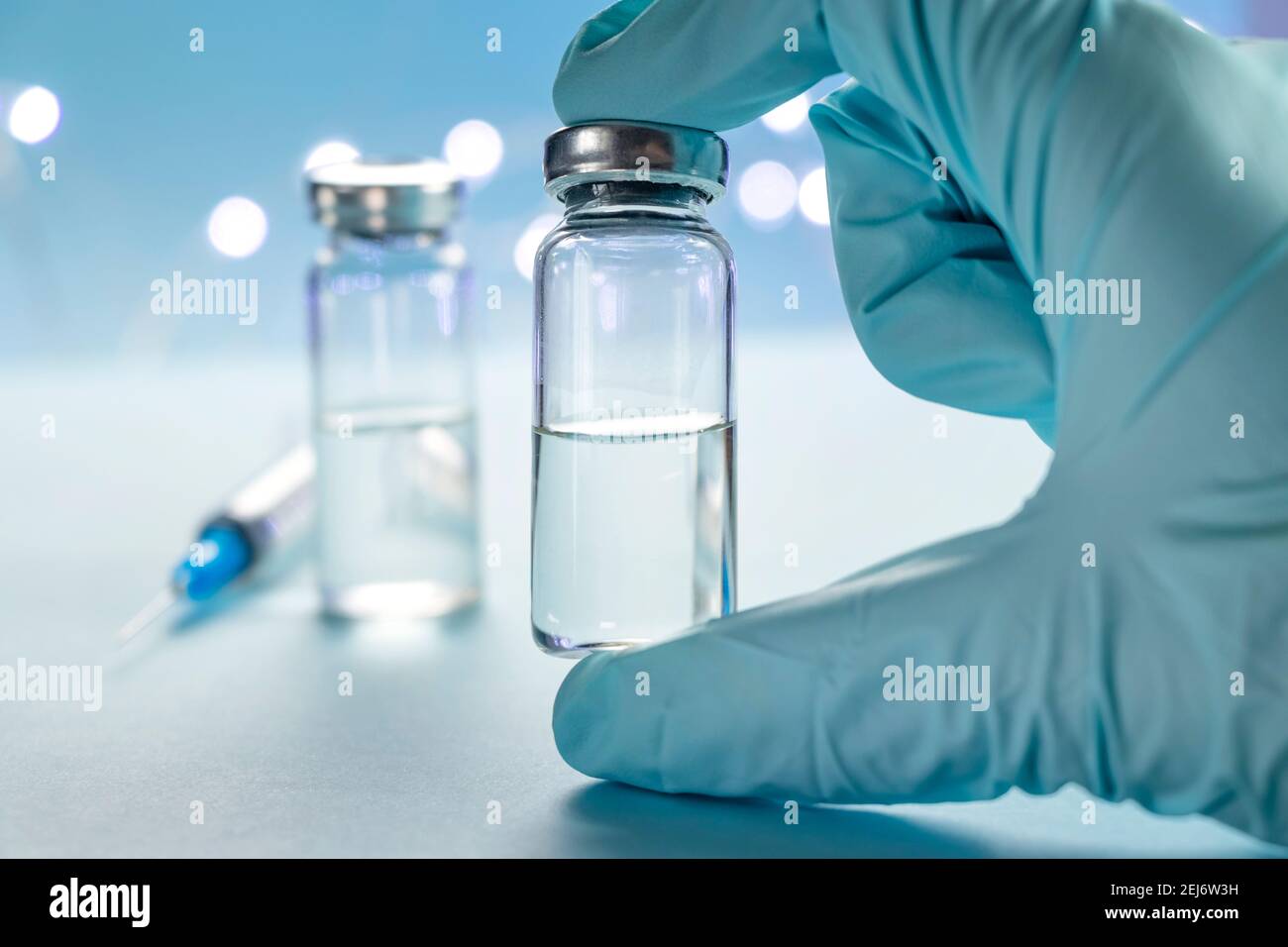 Two bottles of vaccine and syringe injection on blue background ...