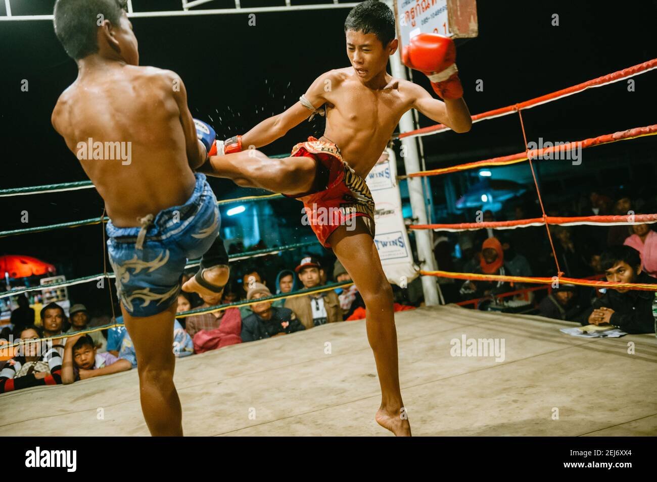 Thai boxing Muay Thai competition, one of the boxers throwing a high kick  at his opponent Stock Photo - Alamy