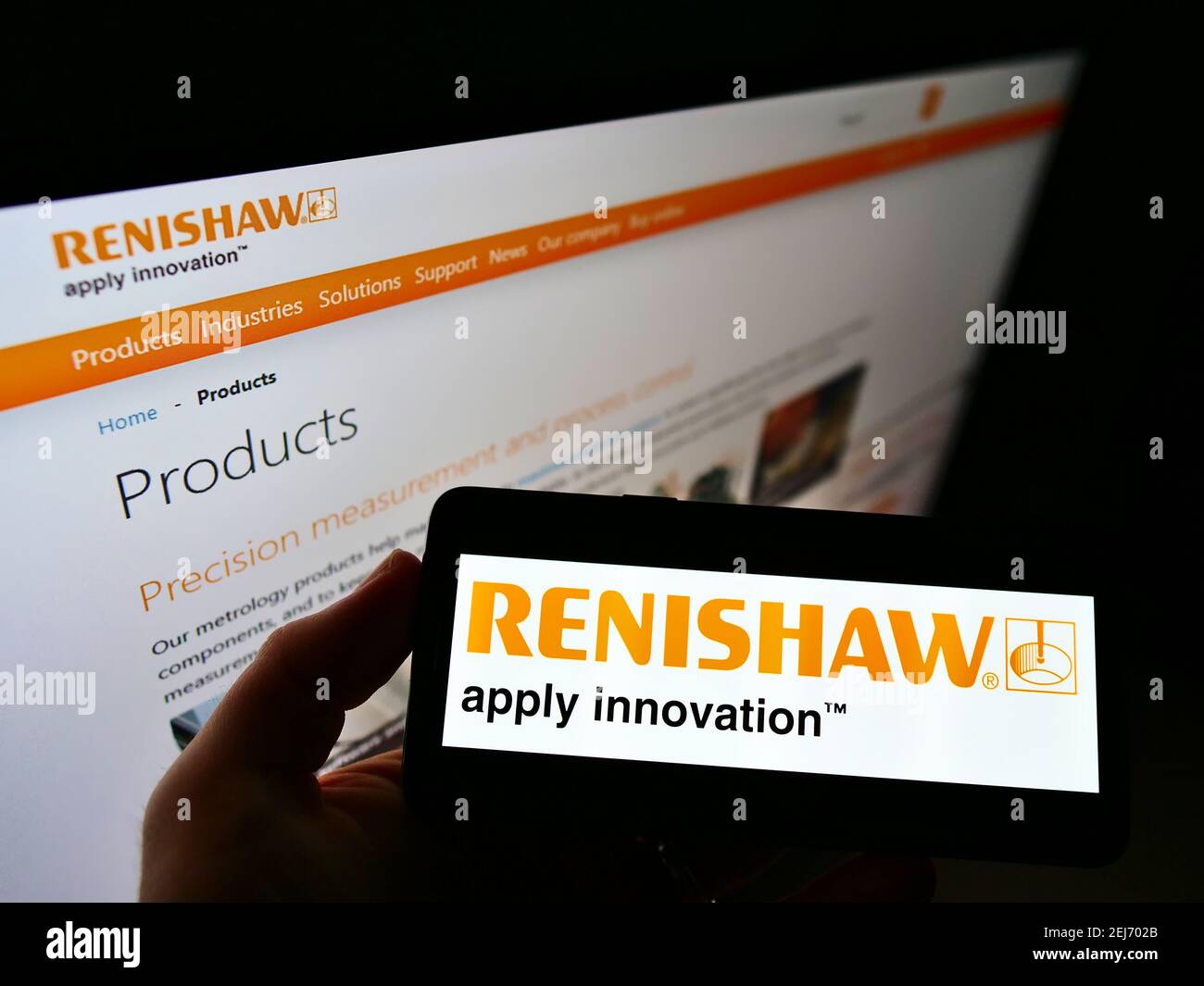 Person holding smartphone with business logo of British engineering company Renishaw plc on screen in front of web page. Focus on cellphone display. Stock Photo