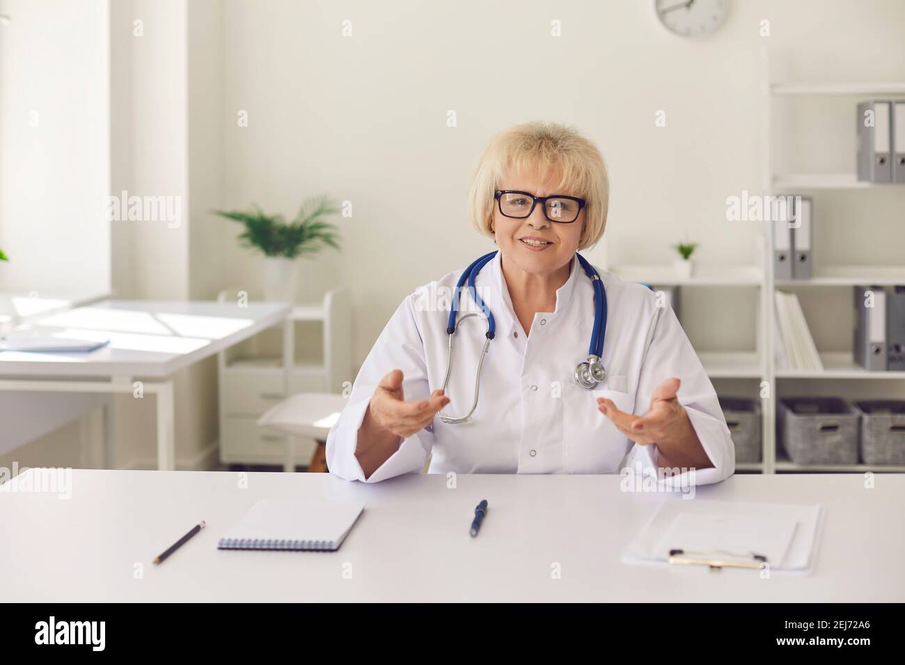 Senior female doctor conducts online consultations and tells her patient about treatment options. Stock Photo