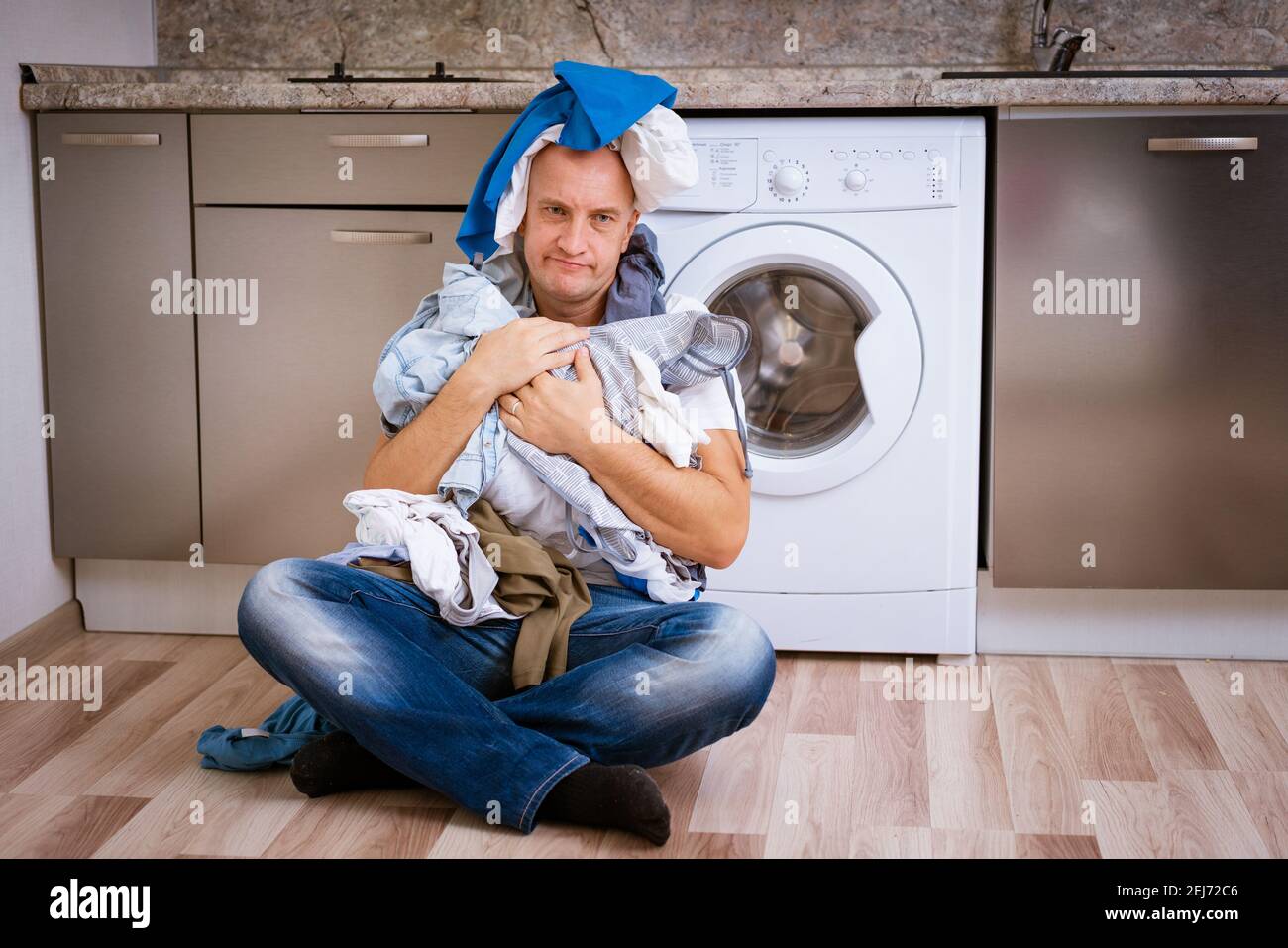 tired bald man sitting with dirty laundry in the washing machine ...