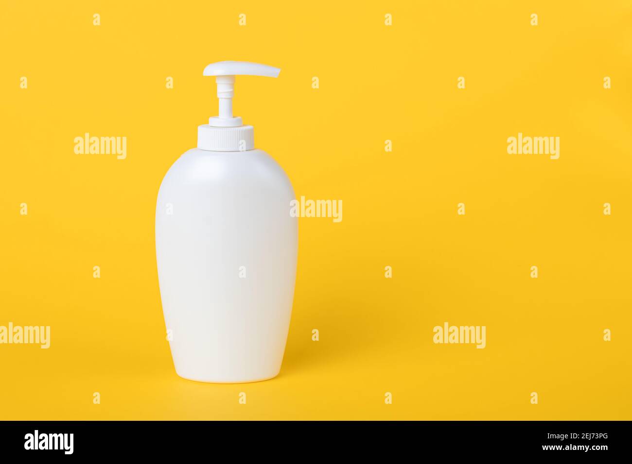 Bottle of liquid soap, white plastic flacon with dispenser on a yellow background. Copy space, empty place for text. Pump lotion. Shower gel for body. Stock Photo