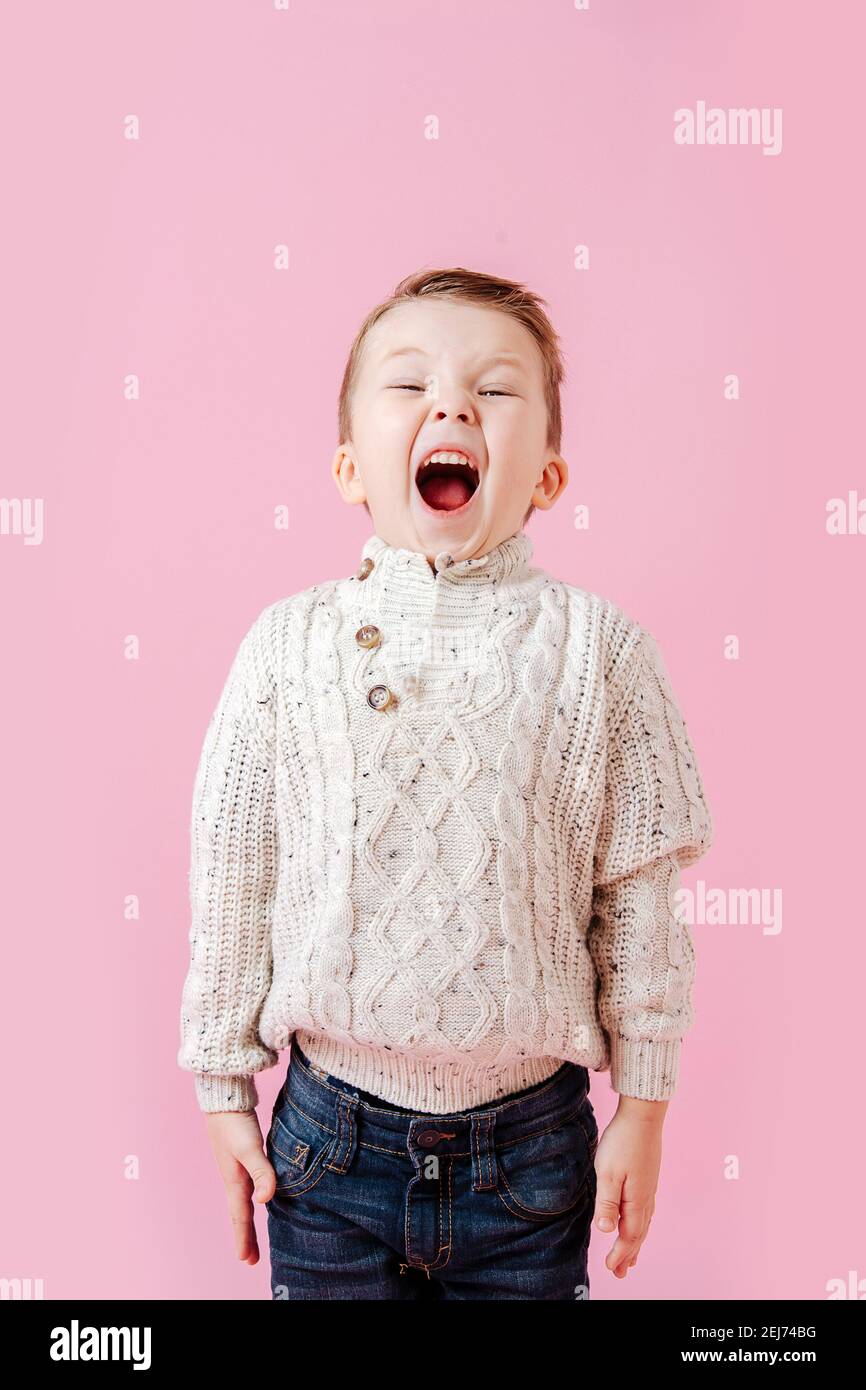 Playful boy standing stiff and tight, mouth open wide, shoulders raised Stock Photo