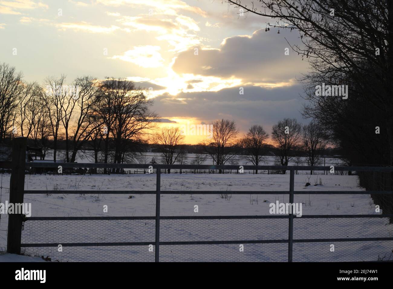 A beautyful sunset with cloudy sky a cattle gate in the foreground Stock Photo