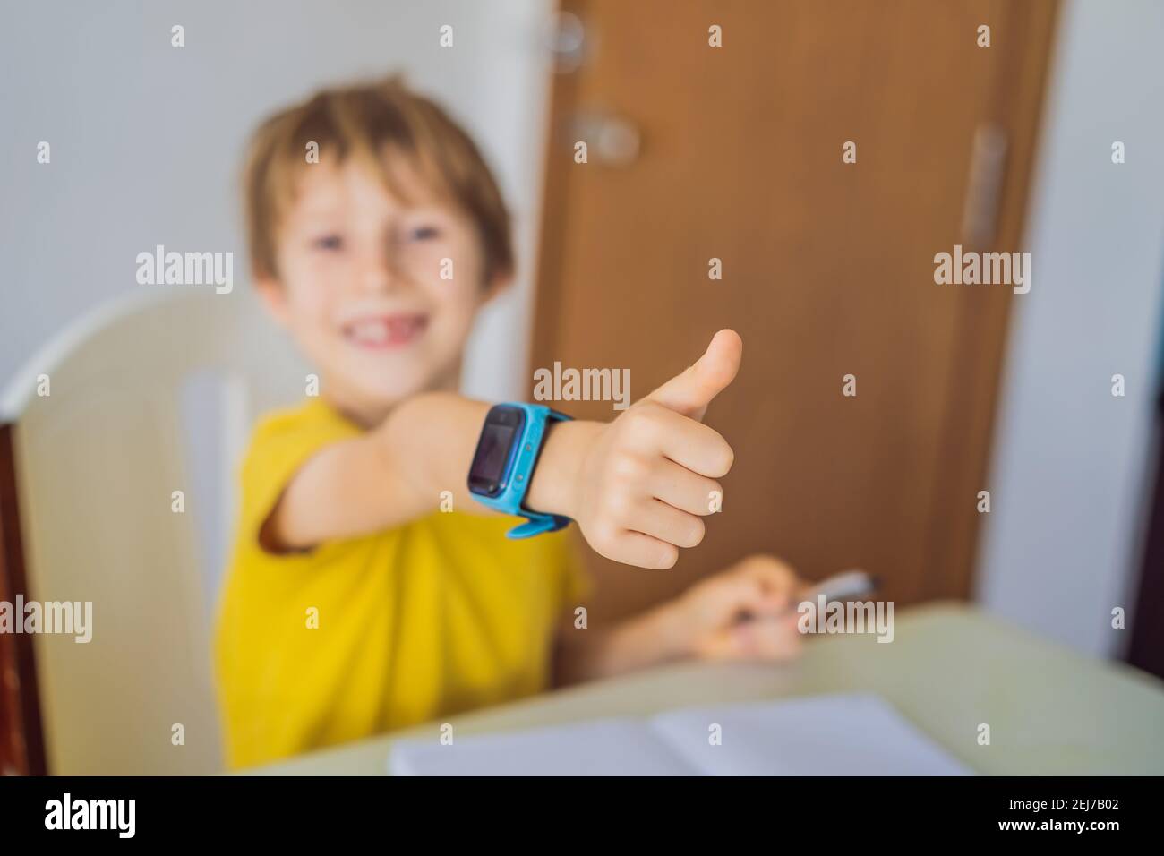 Little boy sitting at the table and looking smart watch. Smart watch
