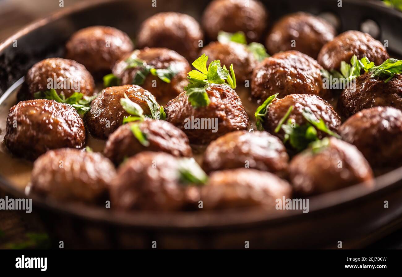 Detail of Swedish meatballs, kottbullar, in a pan topped with fresh parsley. Stock Photo