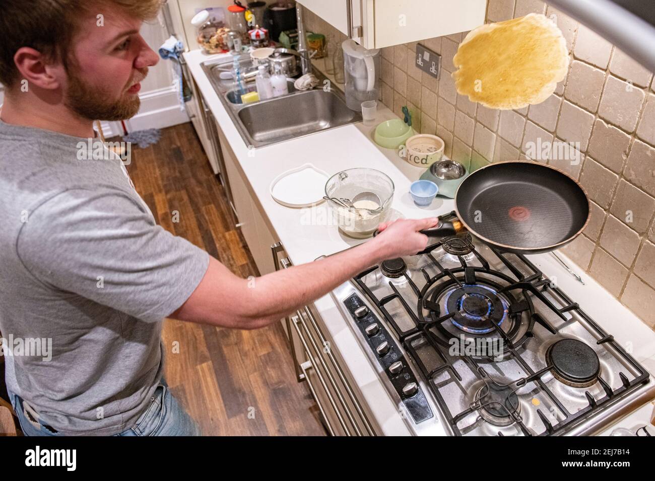 A teenager tosses a pancake on pancake day, Shrove Tuesday Stock Photo