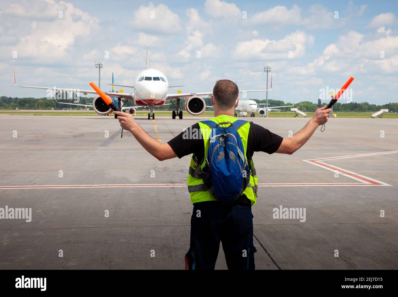 Aviation marshaller meets airplane at the airport. Airport worker. Modern airport. Aviation business. Travel by plane. Airplane flight. Stock Photo