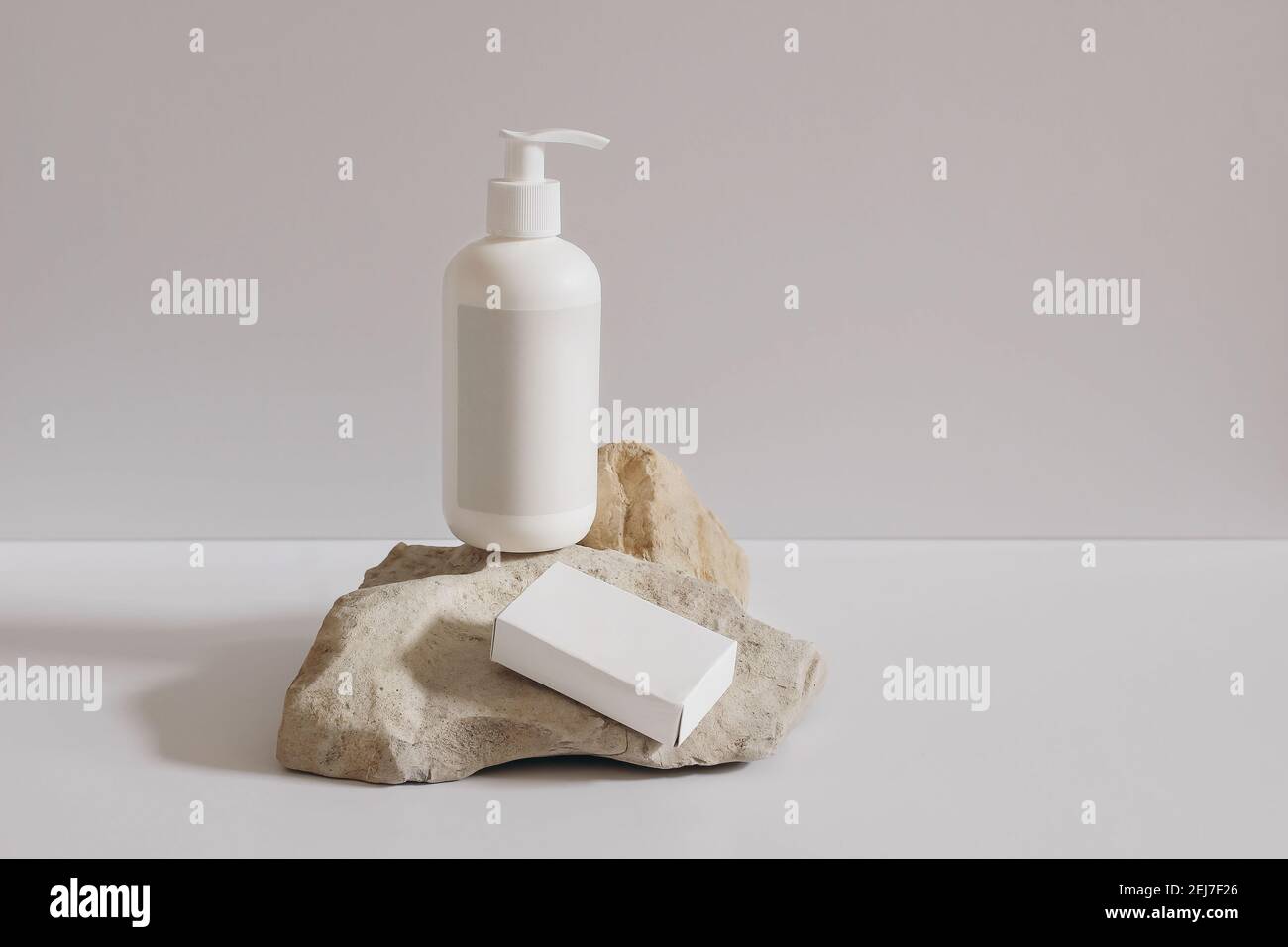 Collection of cosmetic products on beige background. White plastic pump bottle for shampoo, lotion mockup on stone podium. Blank soap paper box Stock Photo