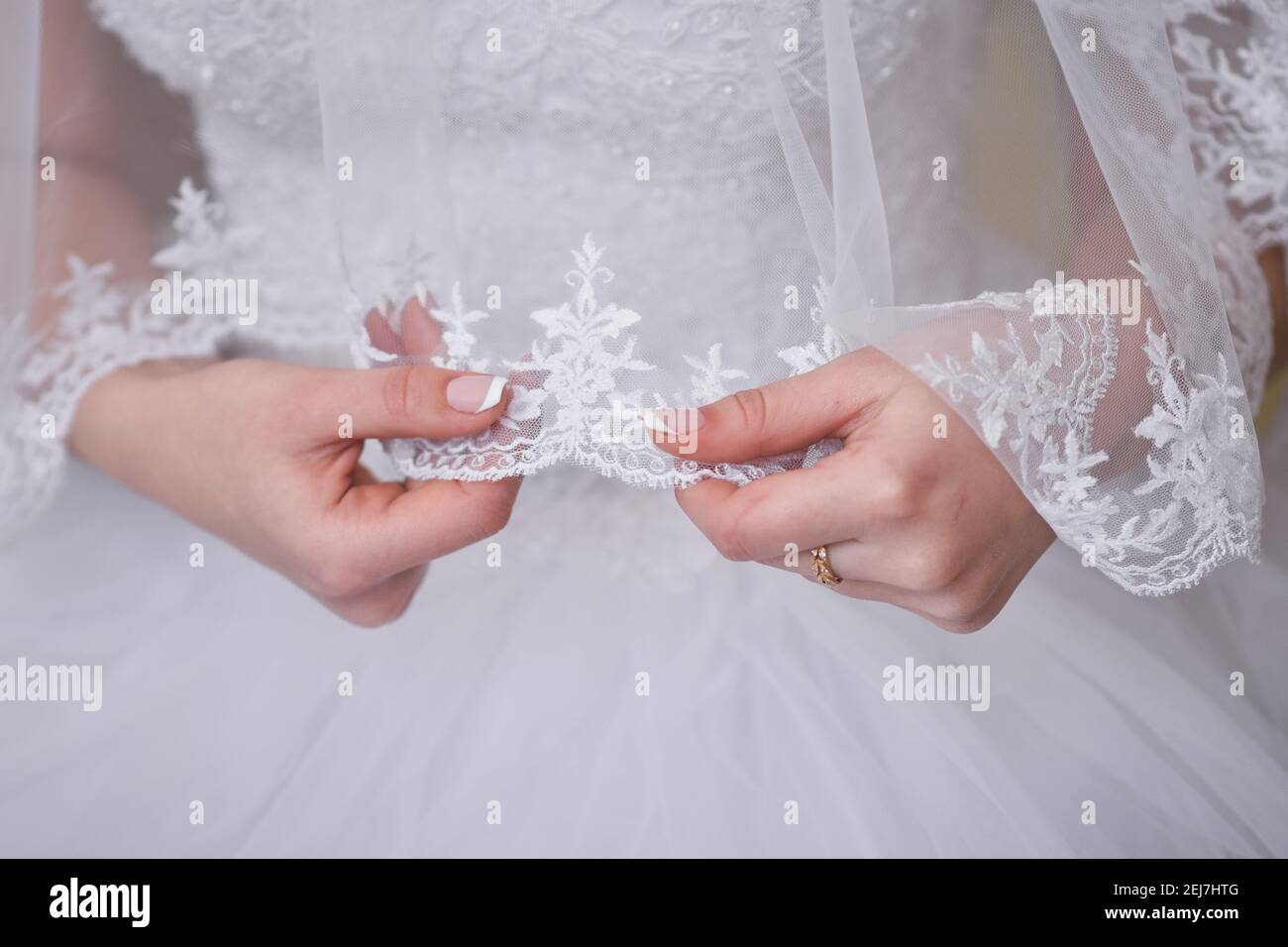 The bride holds a veil in her hands. A bride in a wedding dress.  Stock Photo